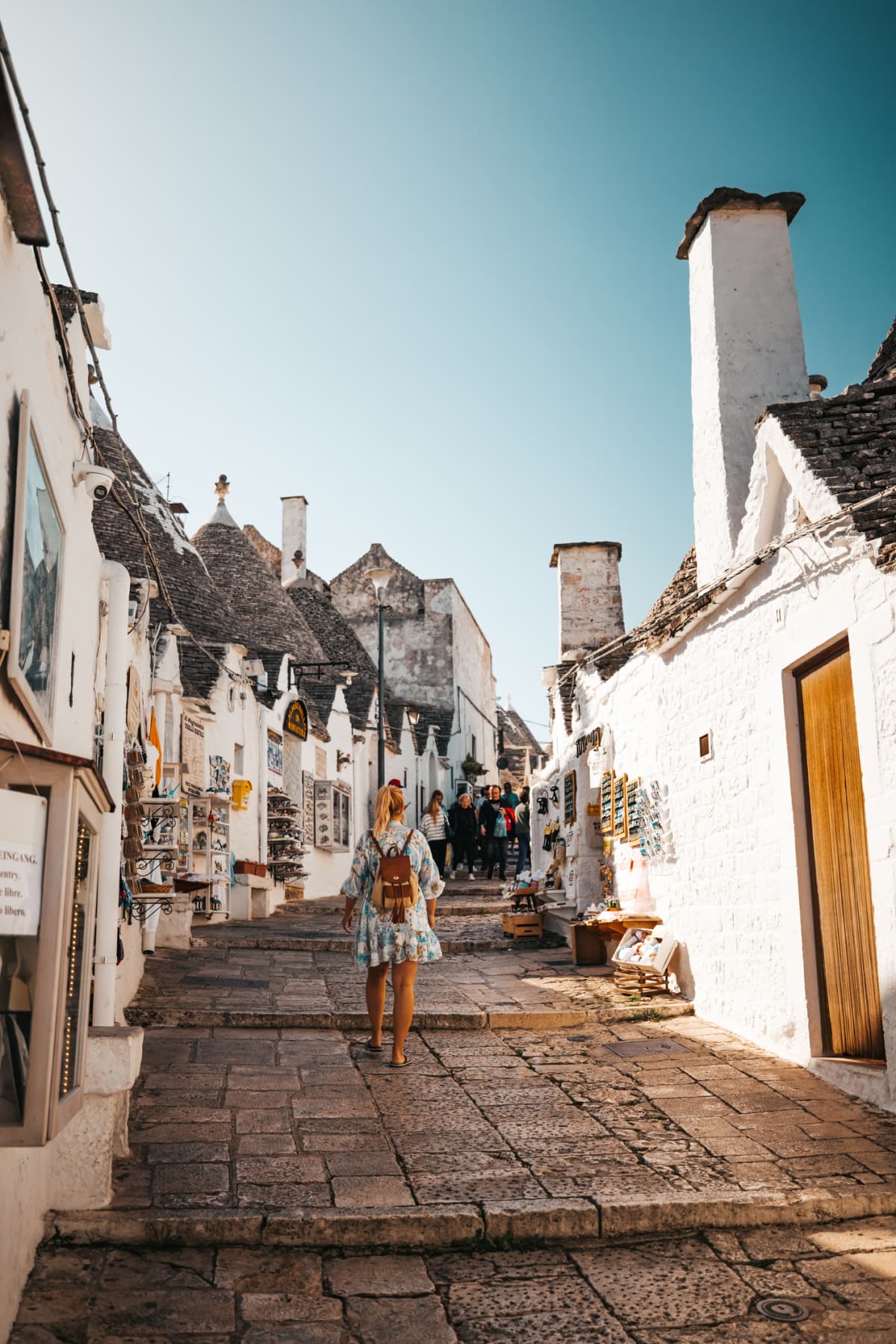 Rear view of woman walking in alley amidst trulli houses