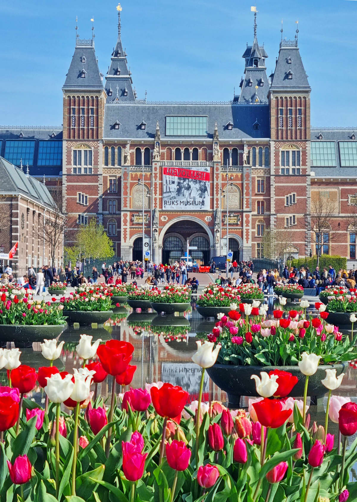 Rijksmuseum on Museumplein with crowds of tourists.