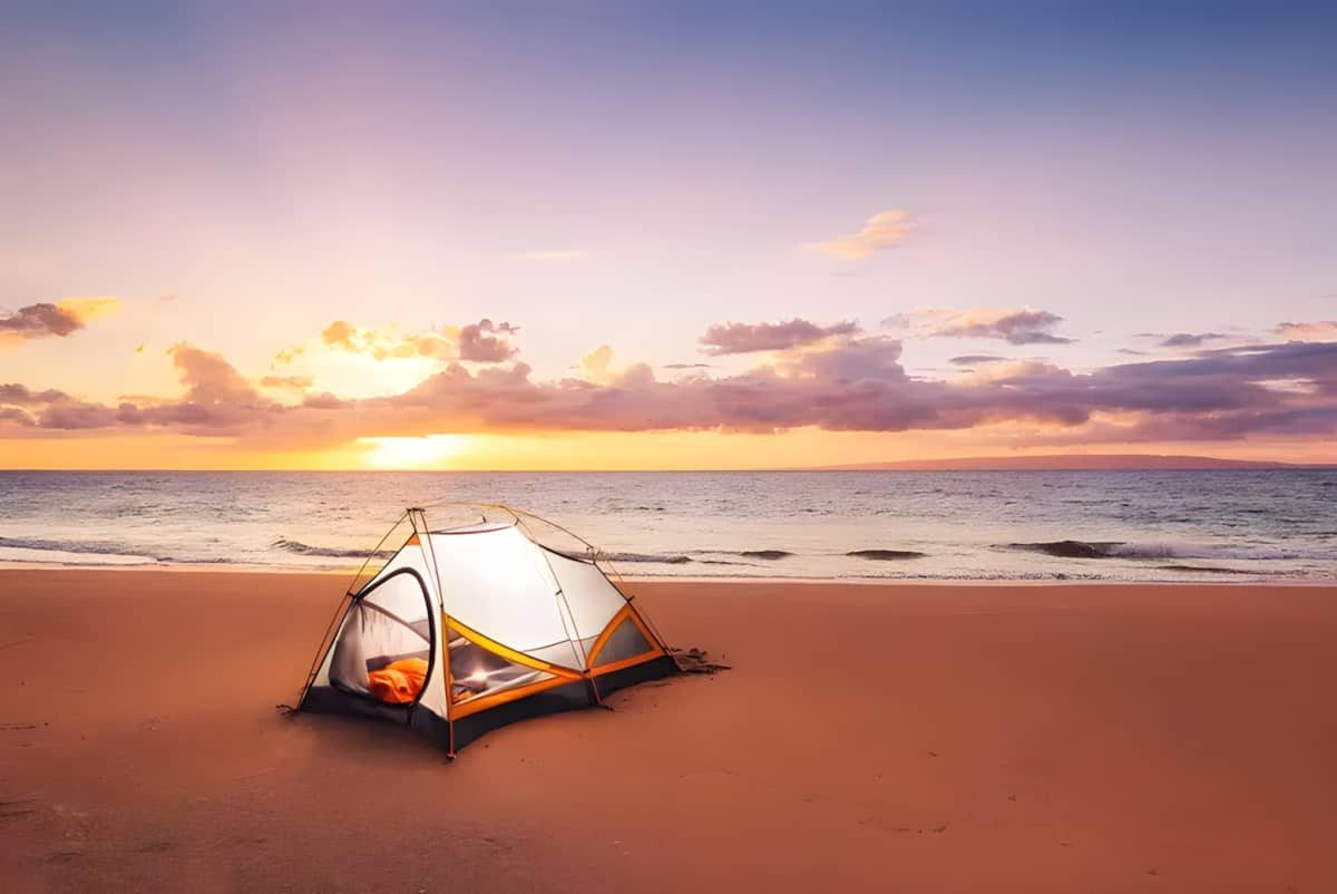 A tent on a beach at sunset