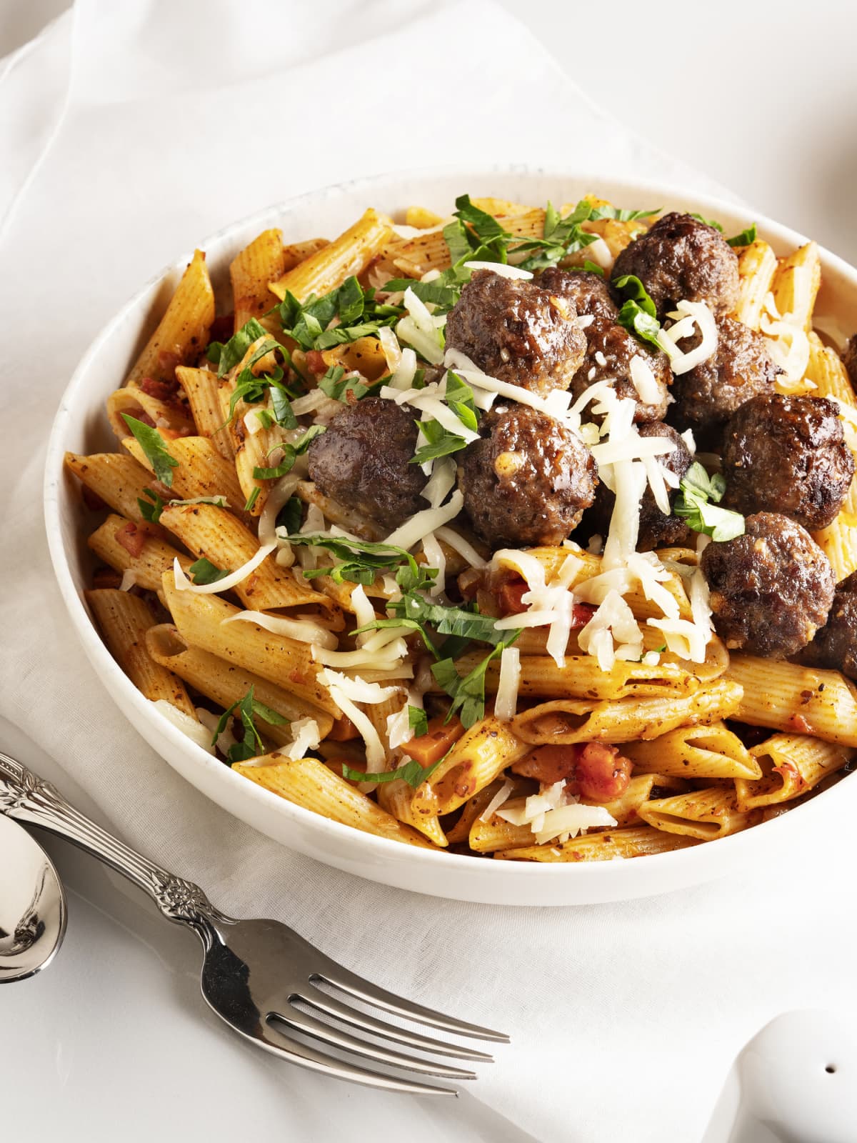 Small meatballs mixed with pasta, cheese, and herbs in a bowl