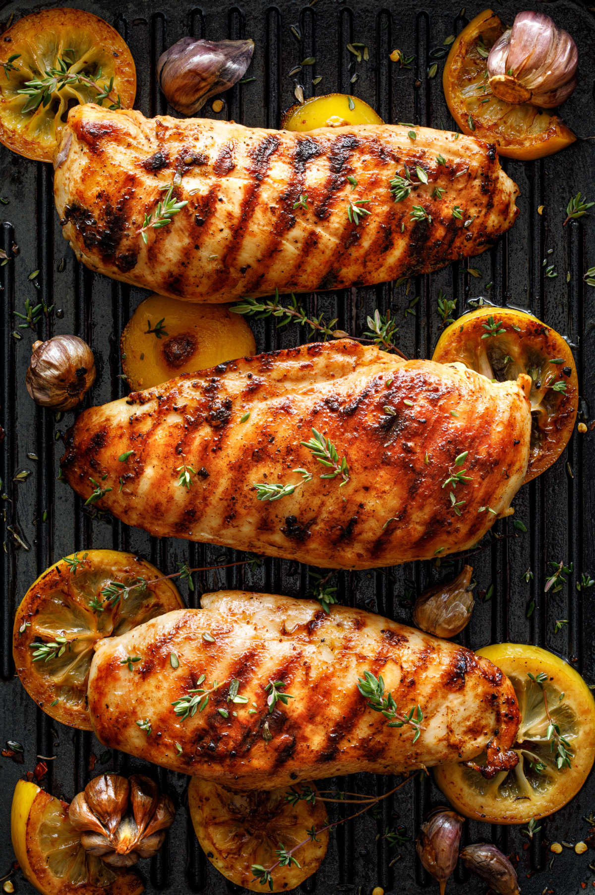 Grilled chicken breasts with thyme, garlic and lemon slices on a grill pan