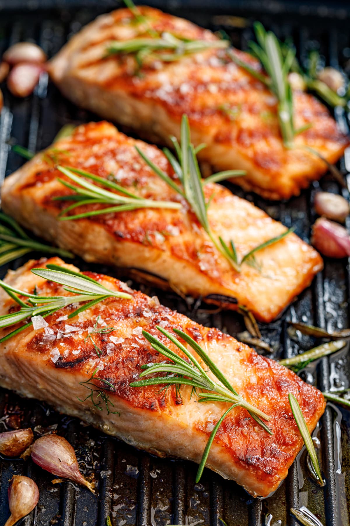 Grilled salmon fillets sprinkled with fresh herbs and lemon juice on a grill plate top view