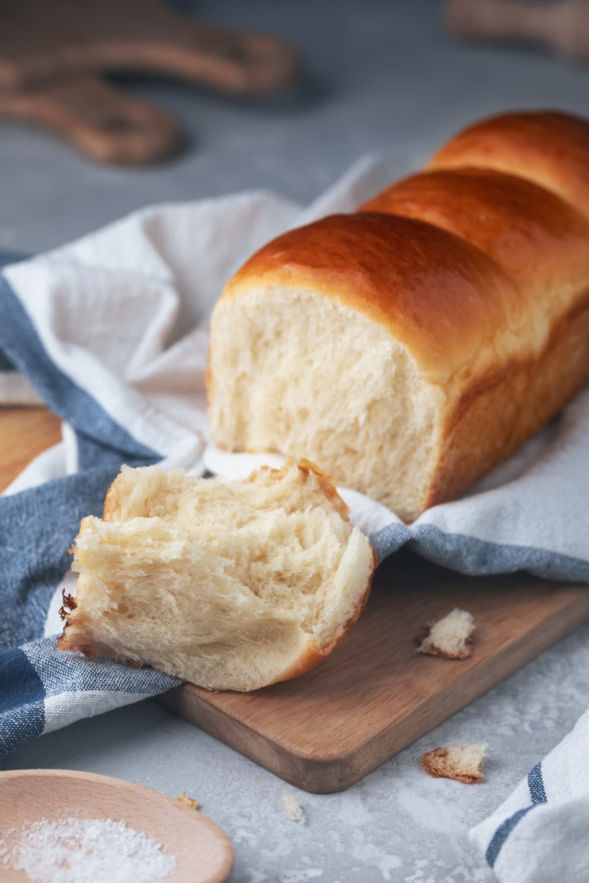 Fresh-baked homemade Hokkaido milk bread on the kitchen towel. Japanese soft and fluffy bread. Cooking at home. Selective focus.