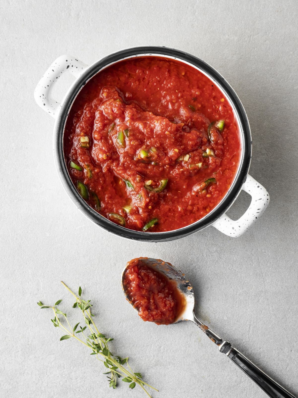 Pot of tomato sauce with herbs on the side