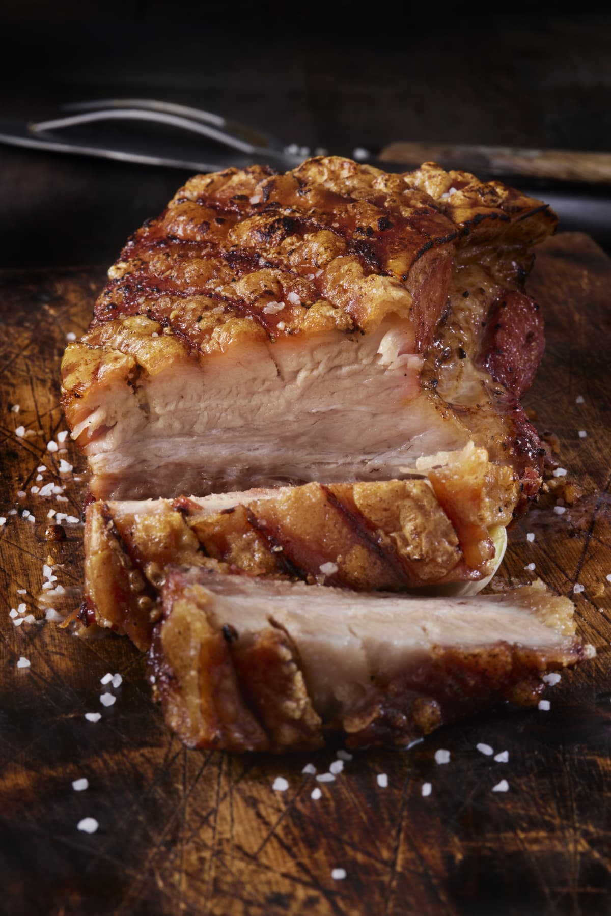 Crispy skin-on pork roast on a wooden cutting board