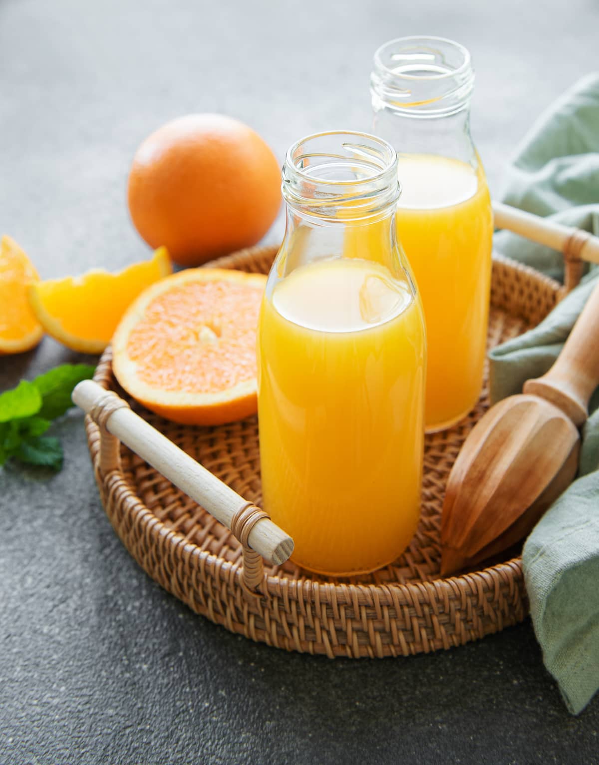 Two jars of orange juice on a tray.