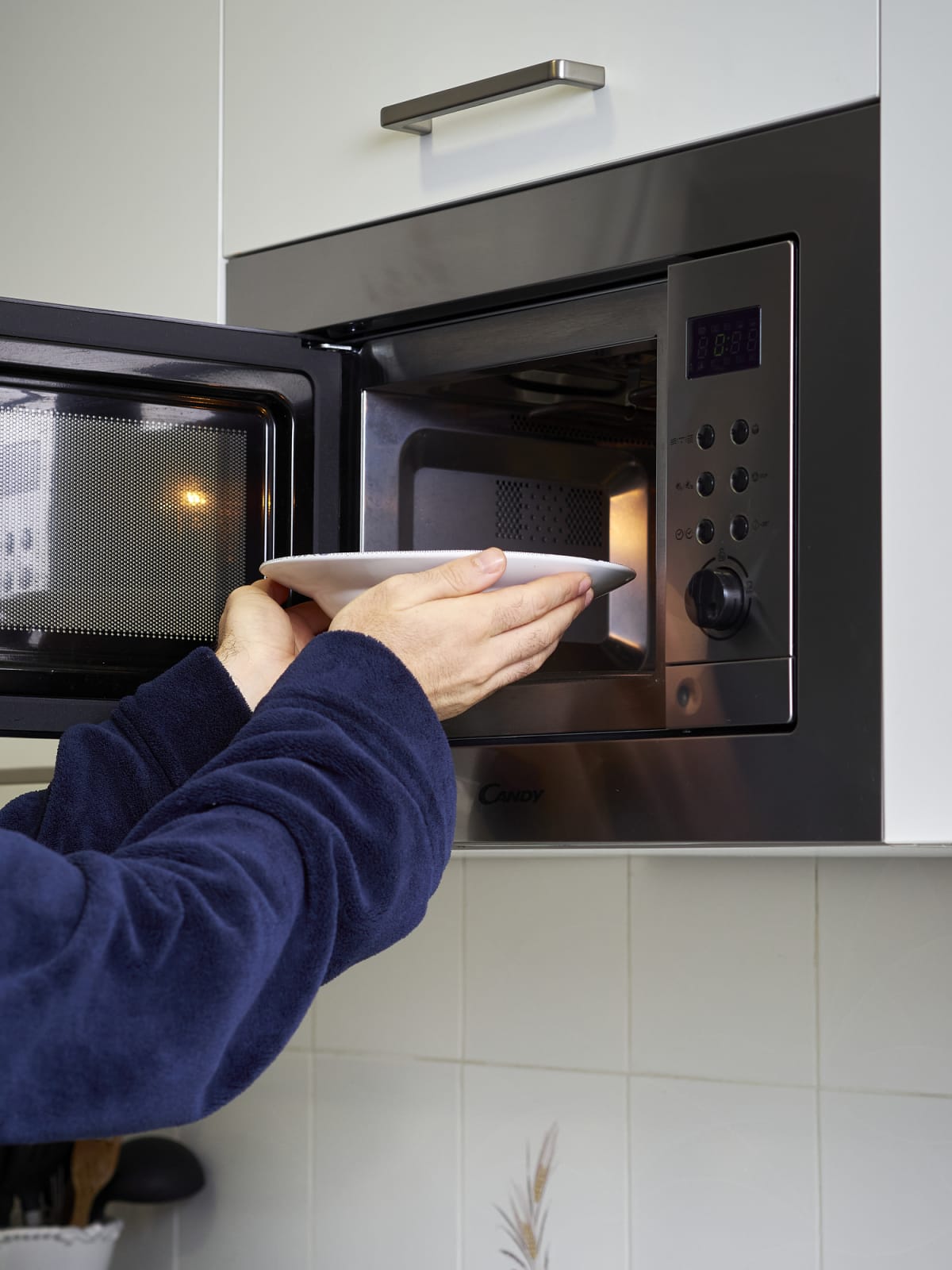 Hands putting a plate into a microwave