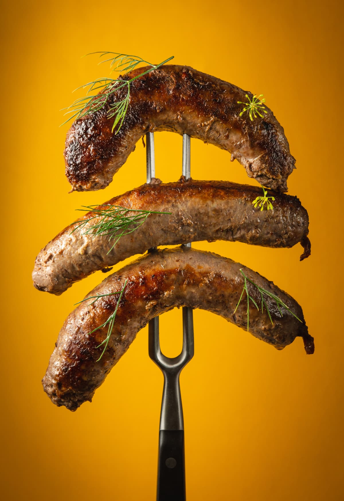 Grilled Bavarian sausages with rosemary.  Sausages  on a fork sprinkled with rosemary.