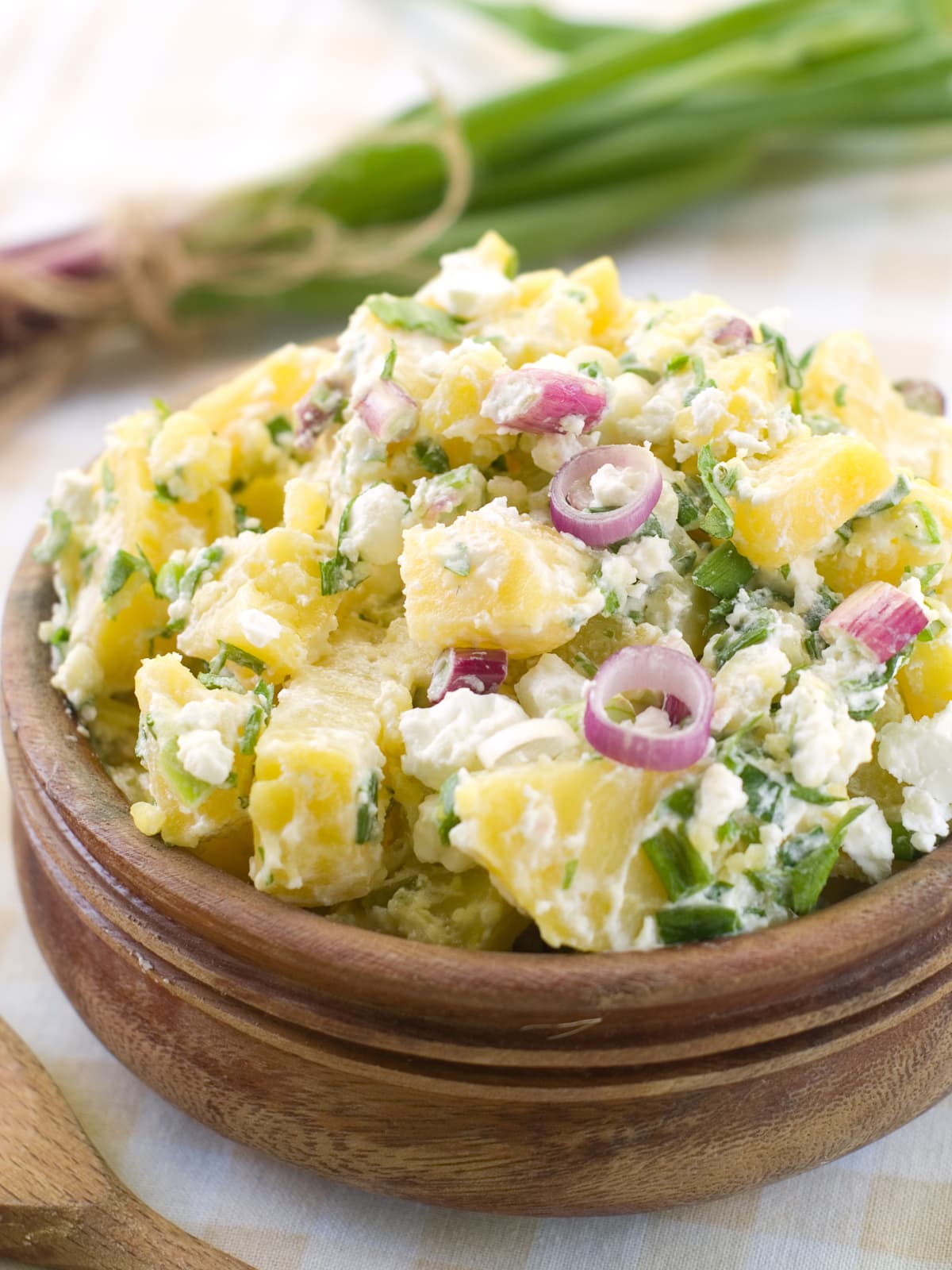 An overflowing bowl of classic potato salad topped with red onion
