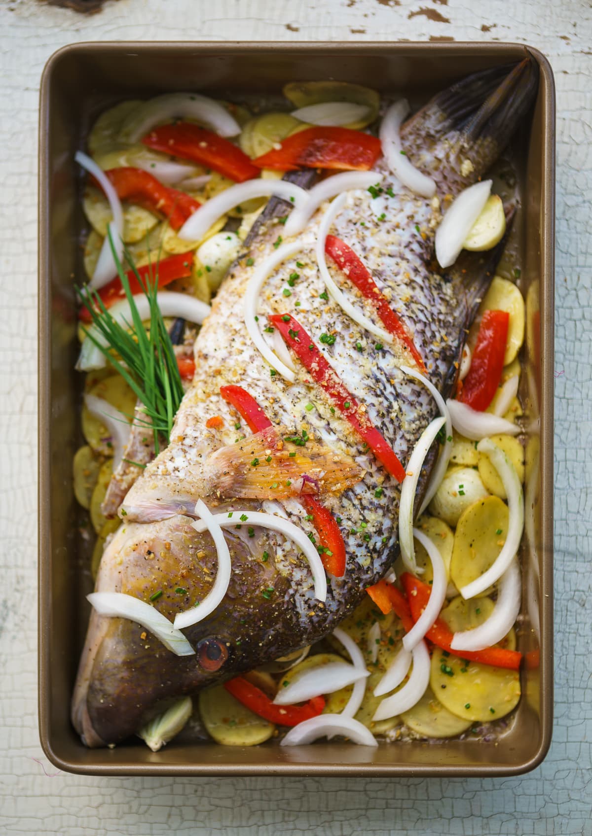 Whole hogfish in a pan with vegetables and fruits