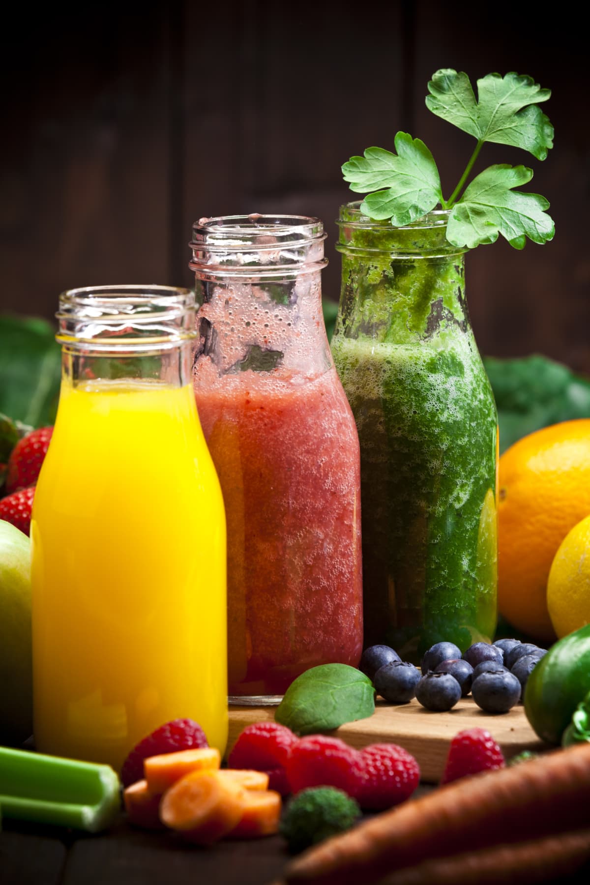 Green red and orange produce juices in glass bottles