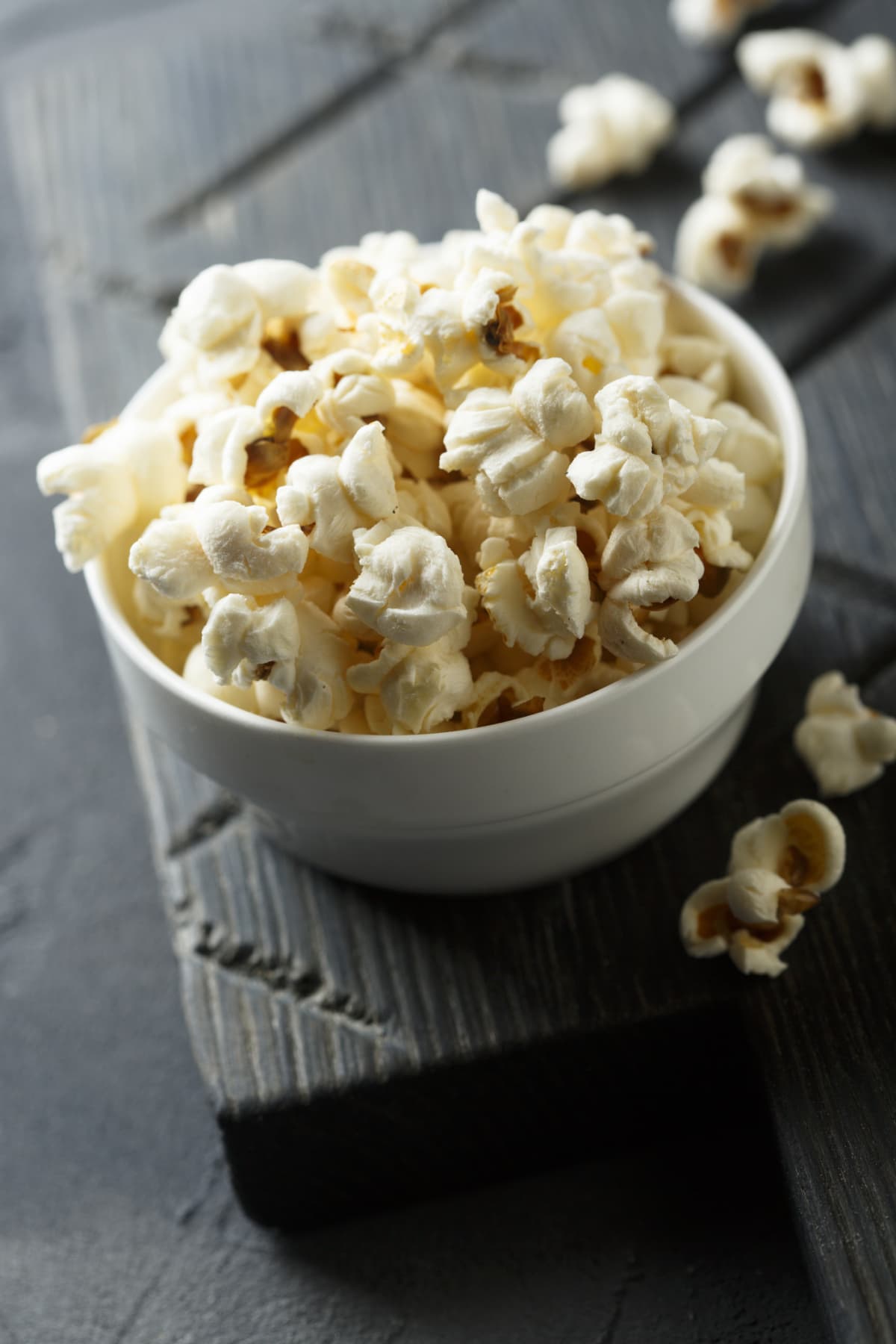 Homemade popcorn in white bowl on dark tray on dark surface