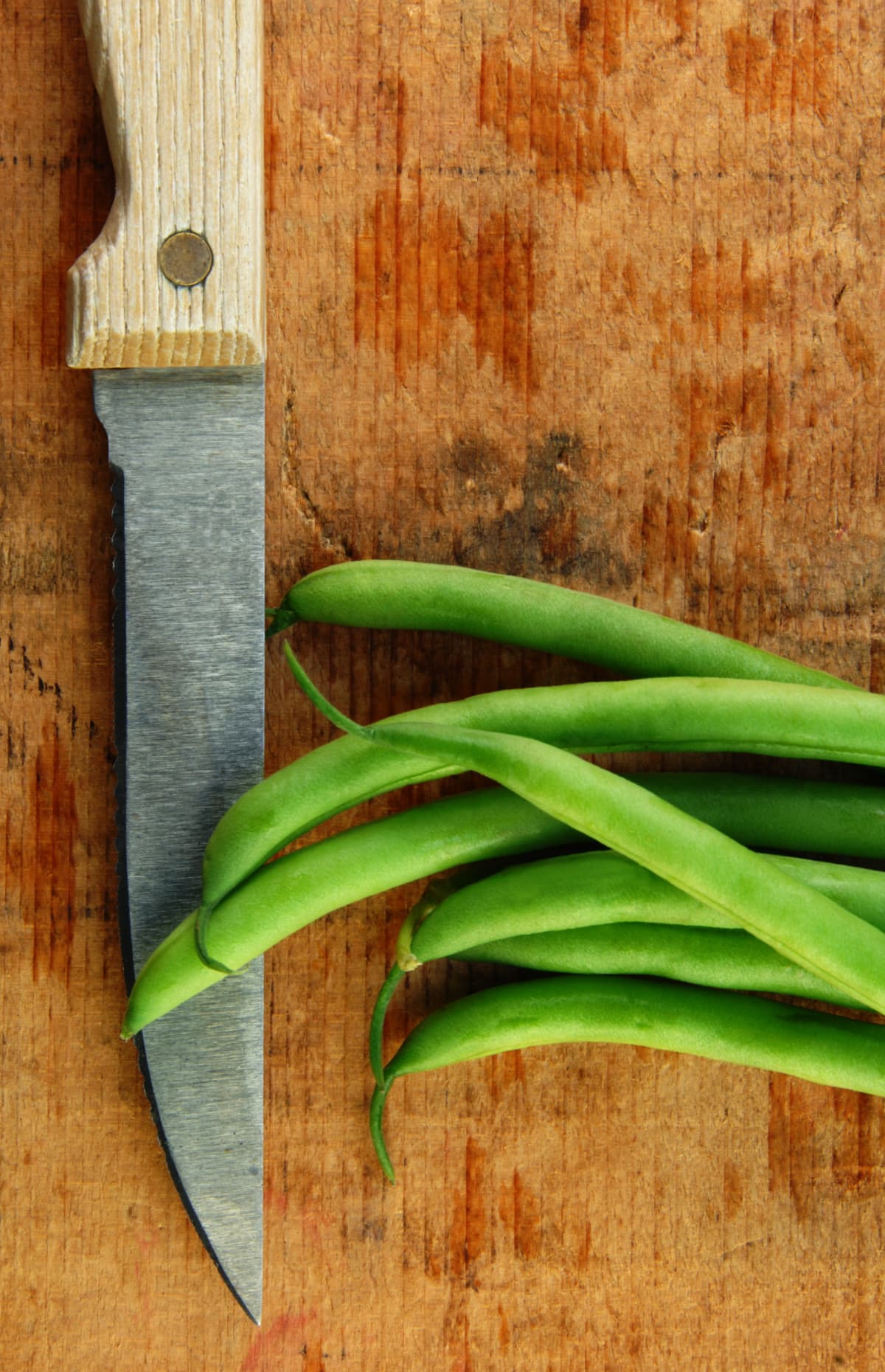 Fresh green beans and knife on a cutting board