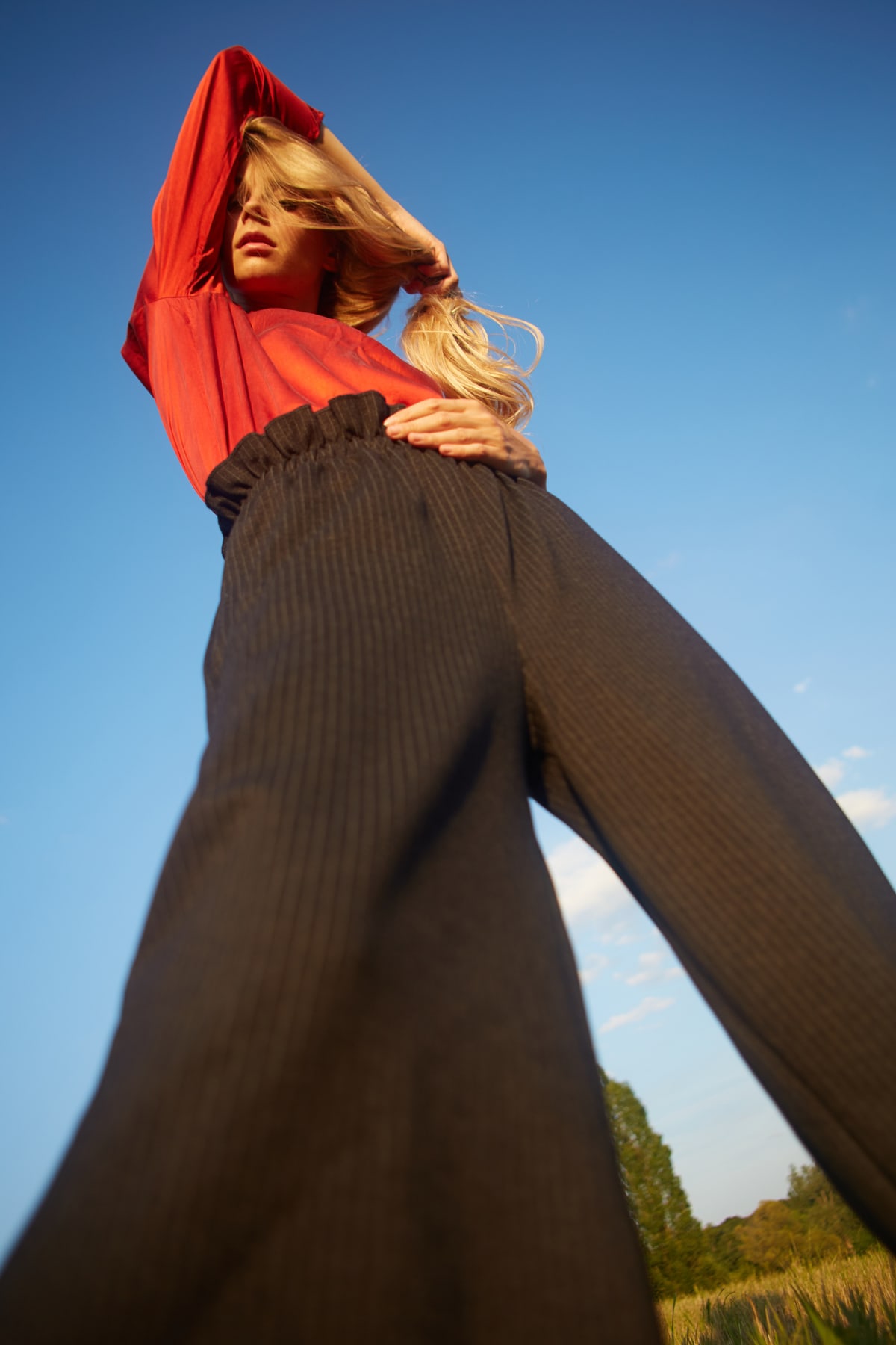 Bottom view of a woman wearing high-waisted brown pants and red top