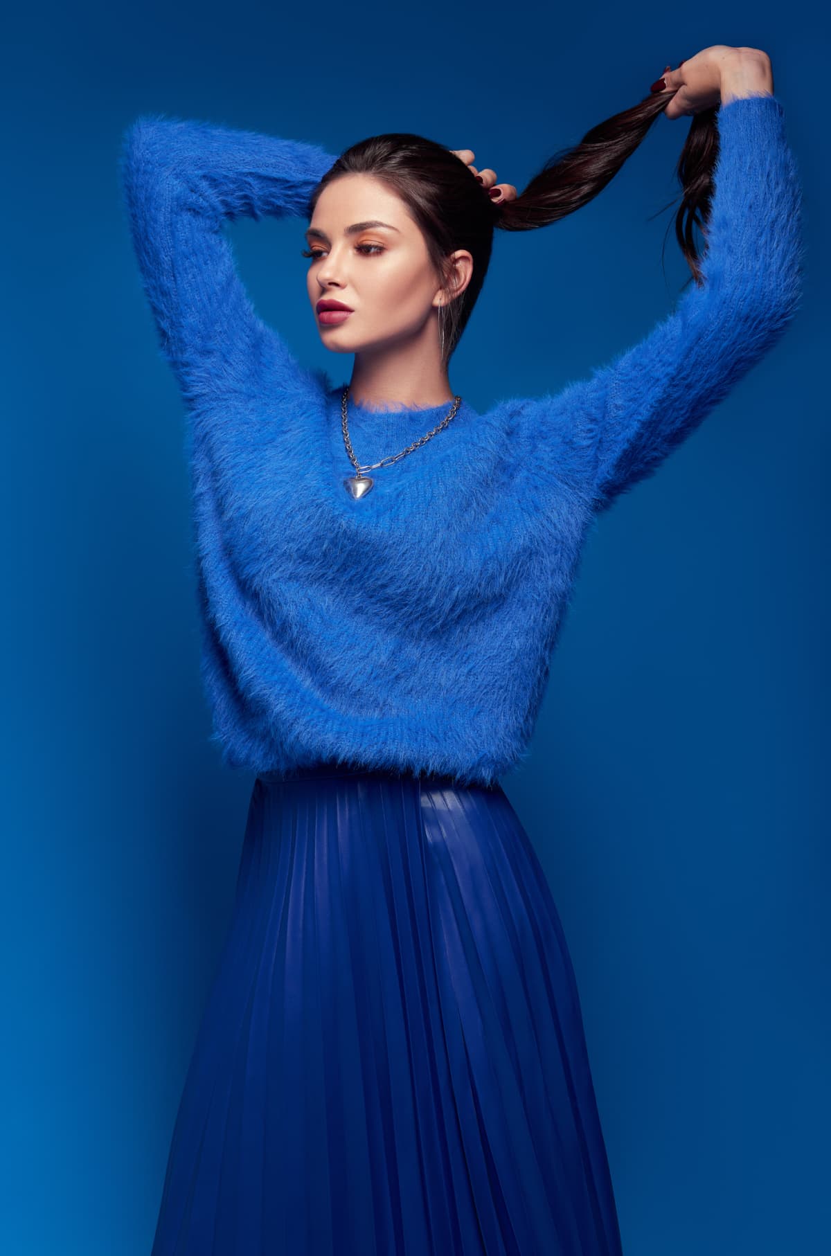 Studio fashion: lovely young woman dressed in blue skirt and sweater.