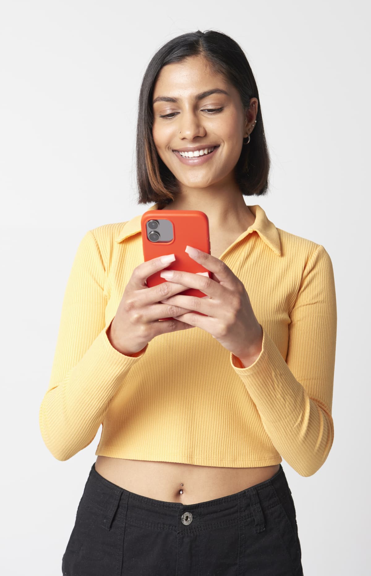 young woman smiling and looking at mobile phone against white background