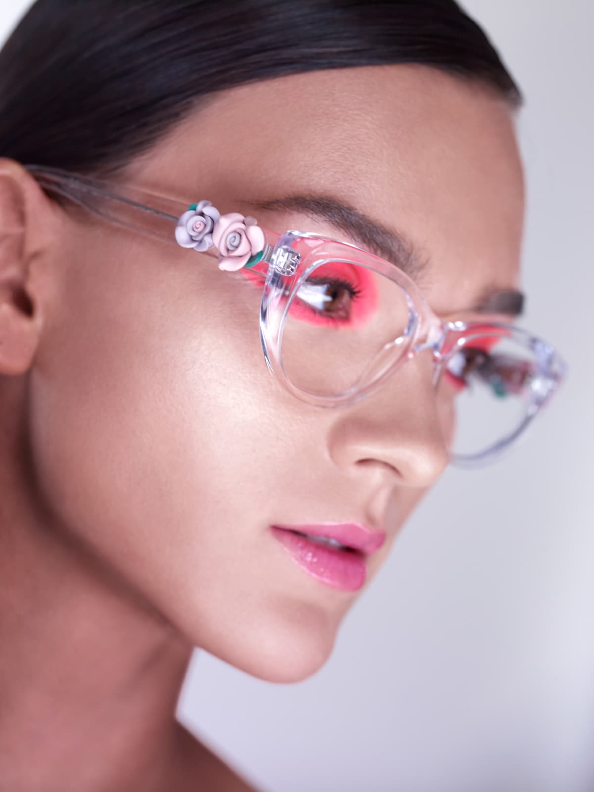 Close up side view of woman wearing clear glasses and pink eye makeup