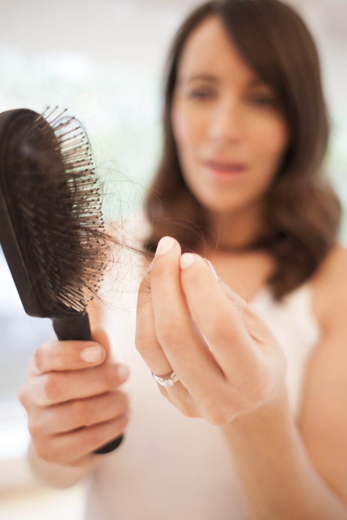 Closeup of a brush with a woman pulling hair off of it