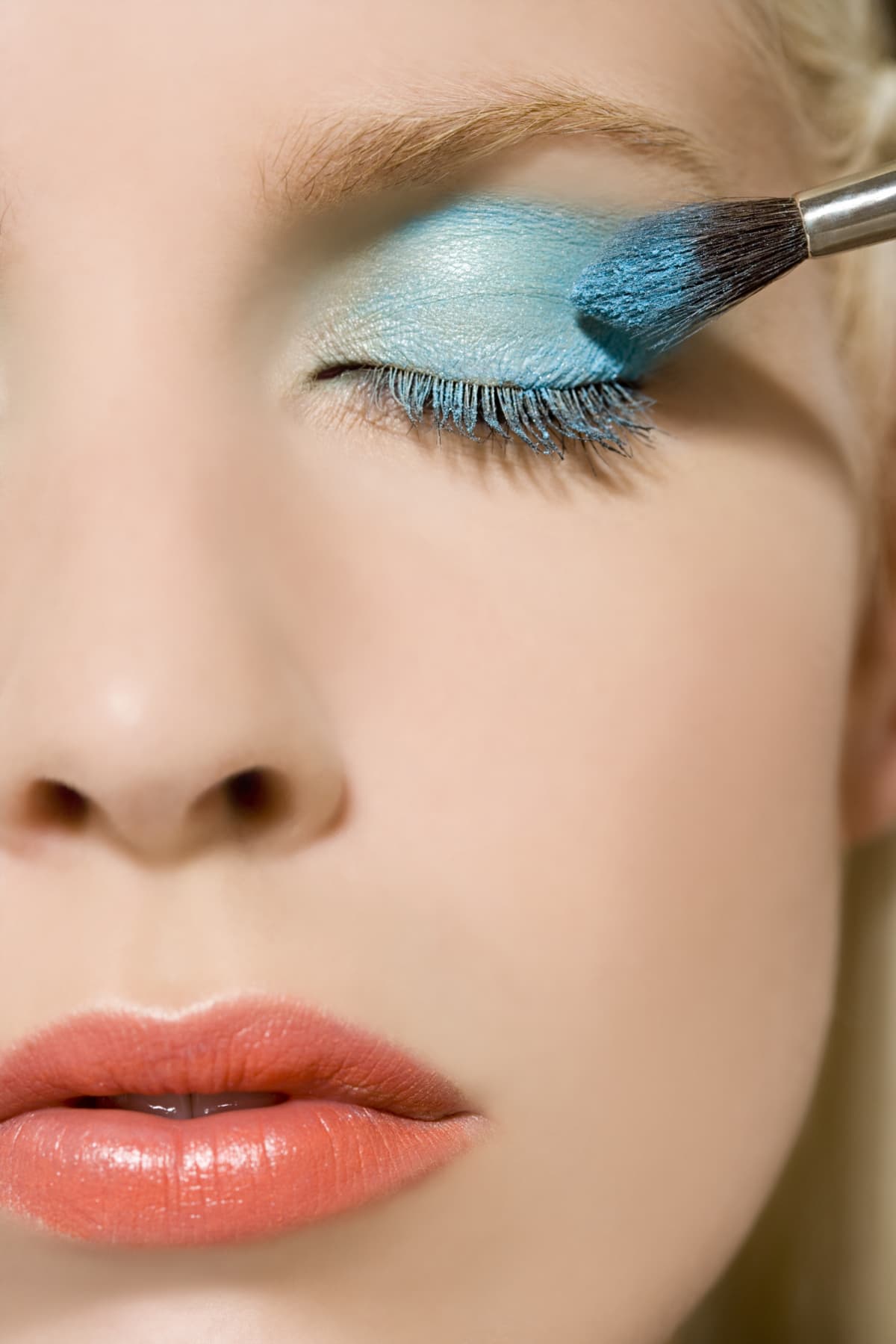 Woman applying light blue eyeshadow