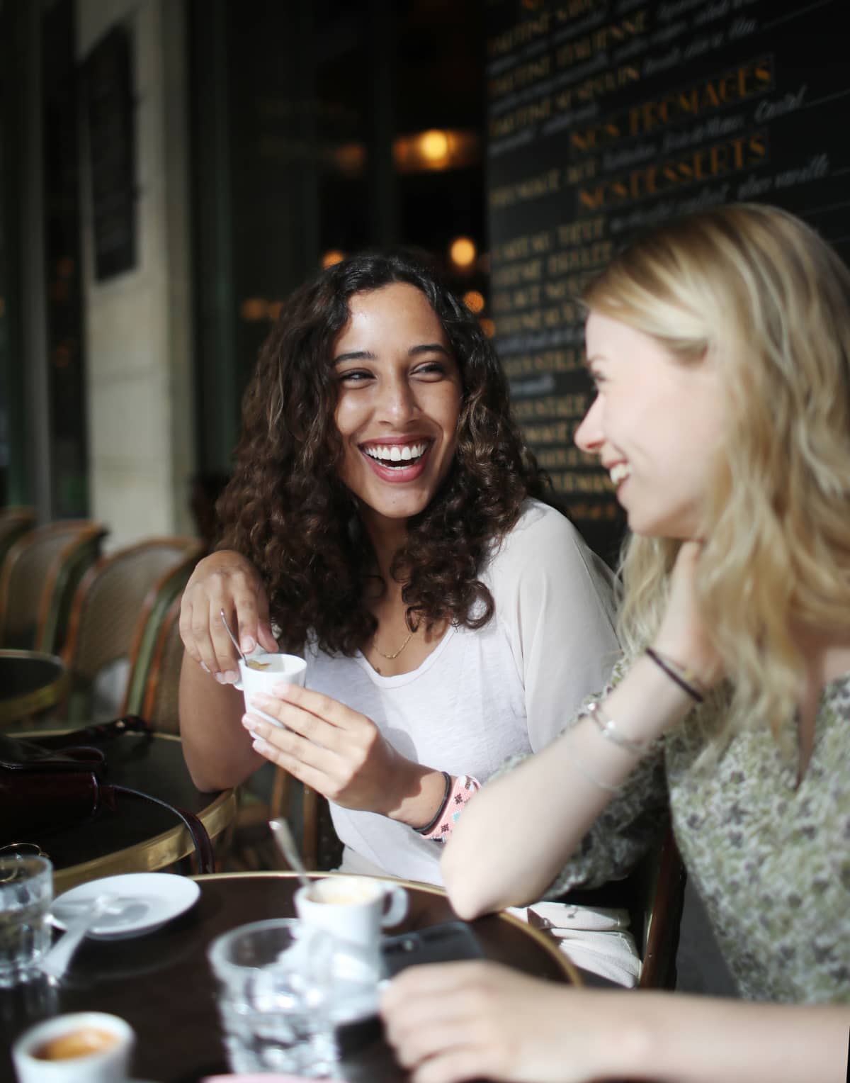 Two smiling women enjoying cups of coffee