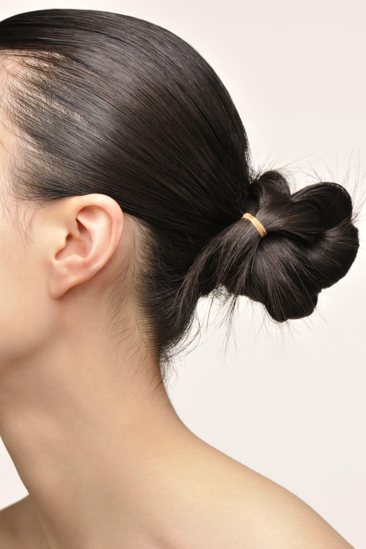 Woman's profile with her hair tied in a bun at the base of her head