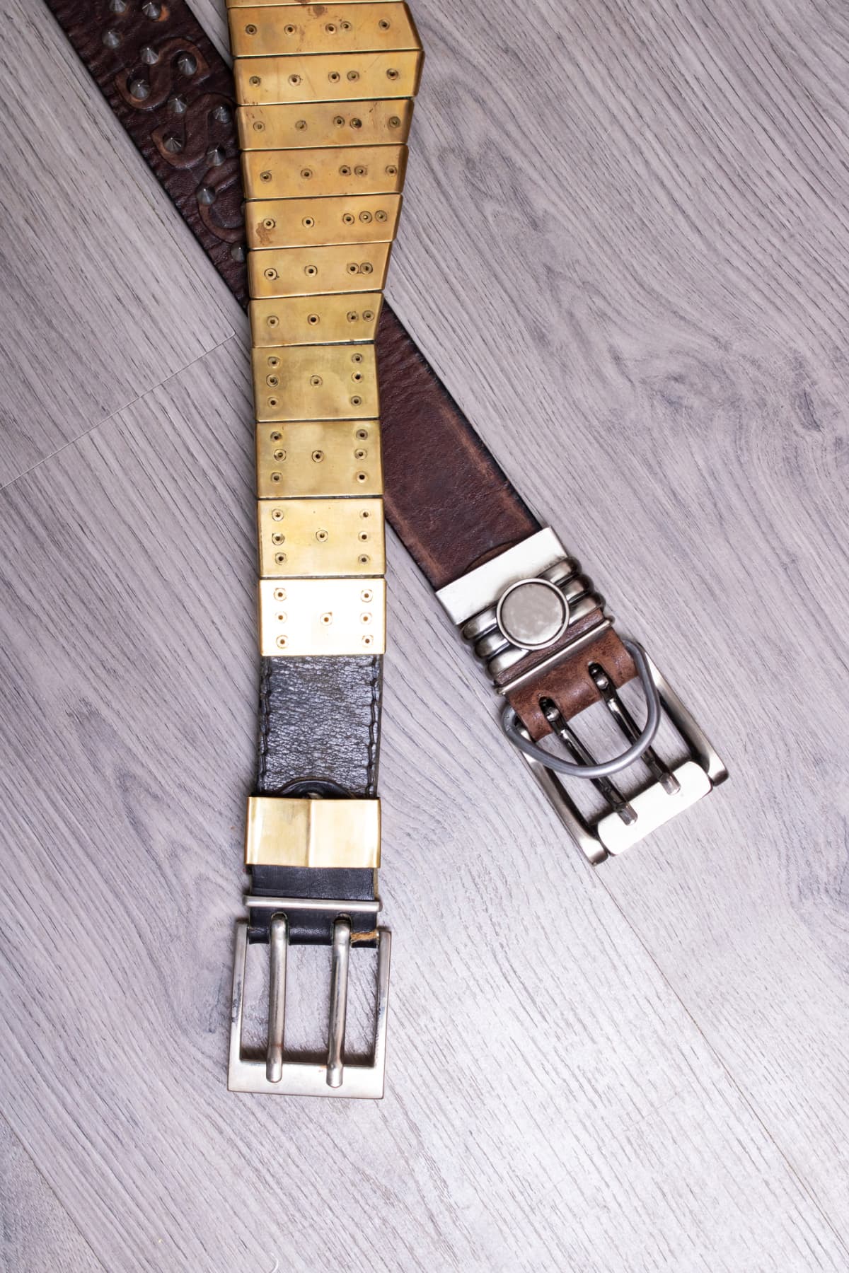 Two leather belts on a wooden background close up