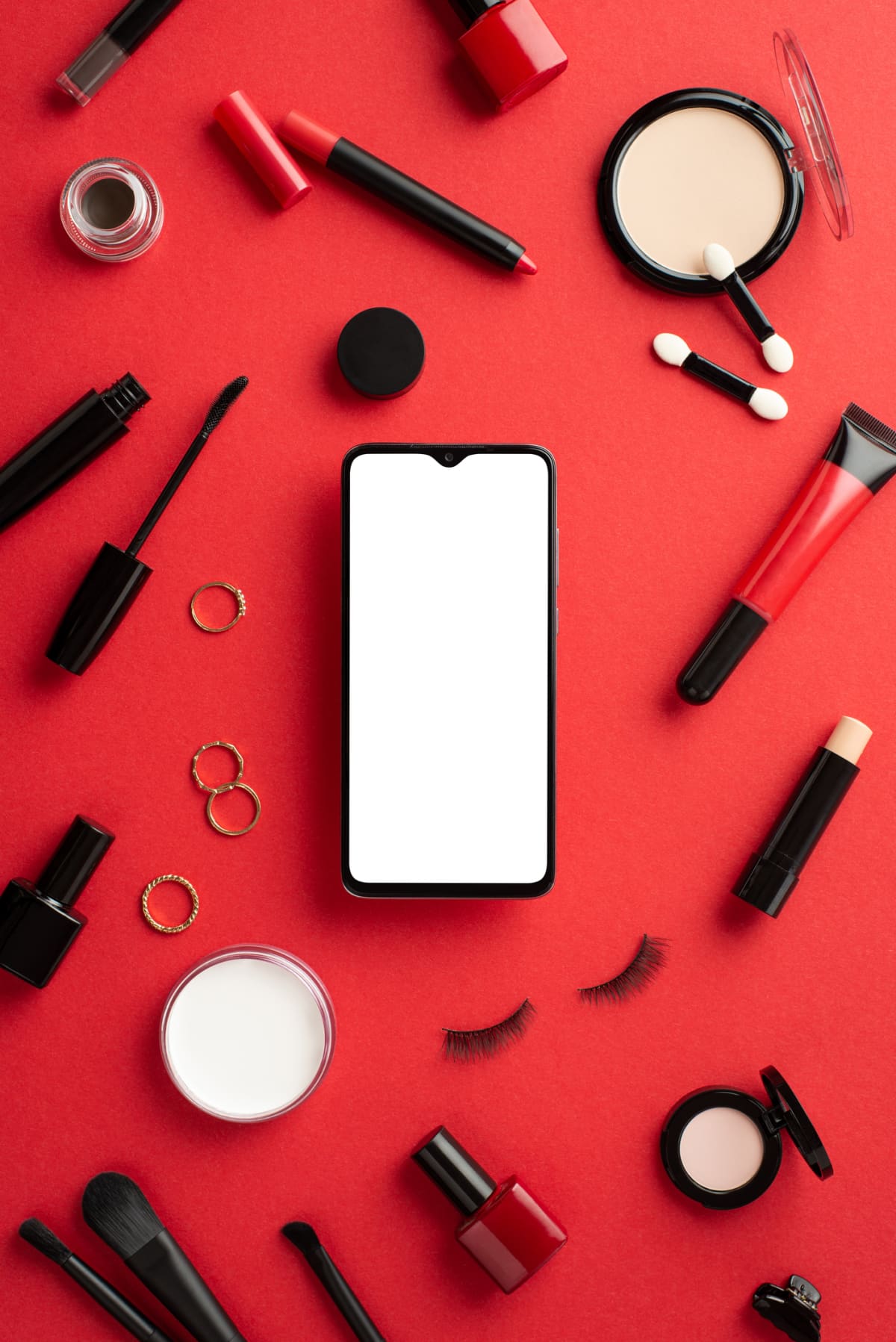 Black friday concept. Top view vertical photo of smartphone mascara false eyelashes eyeshadow nail polish lashes curler powder eyebrow gel barrette brushes on isolated red background with copyspace