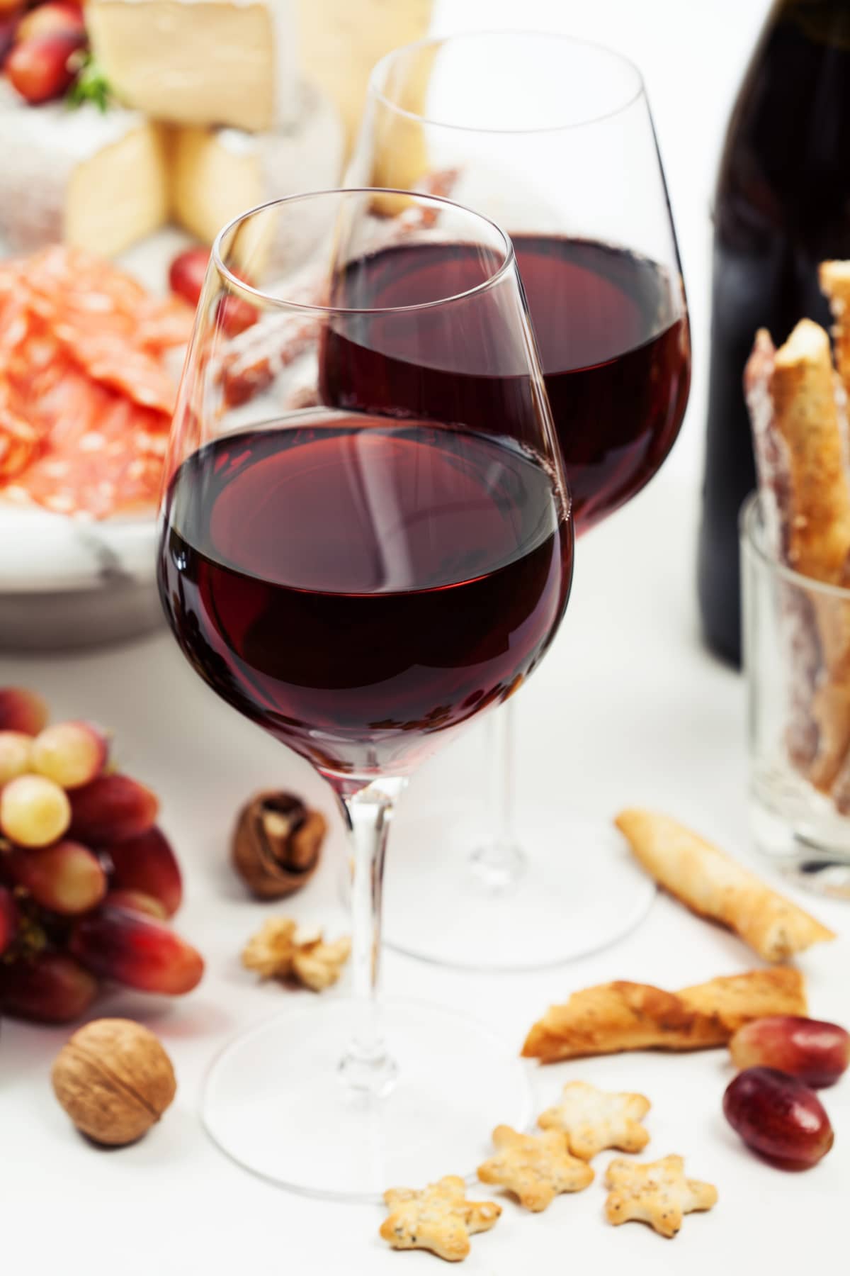 Bottle of red wine, grapes and cheese isolated on white