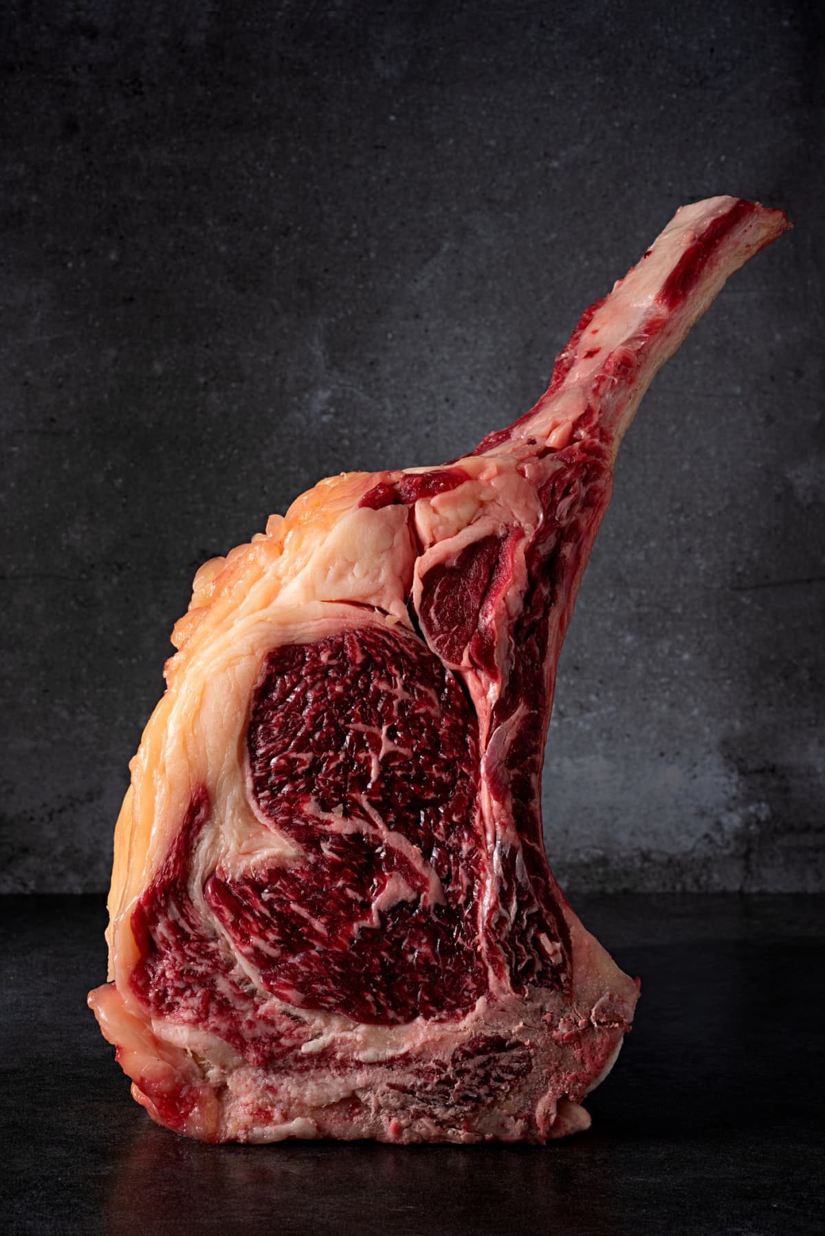 Dry-aged Angus rib steak on black surface