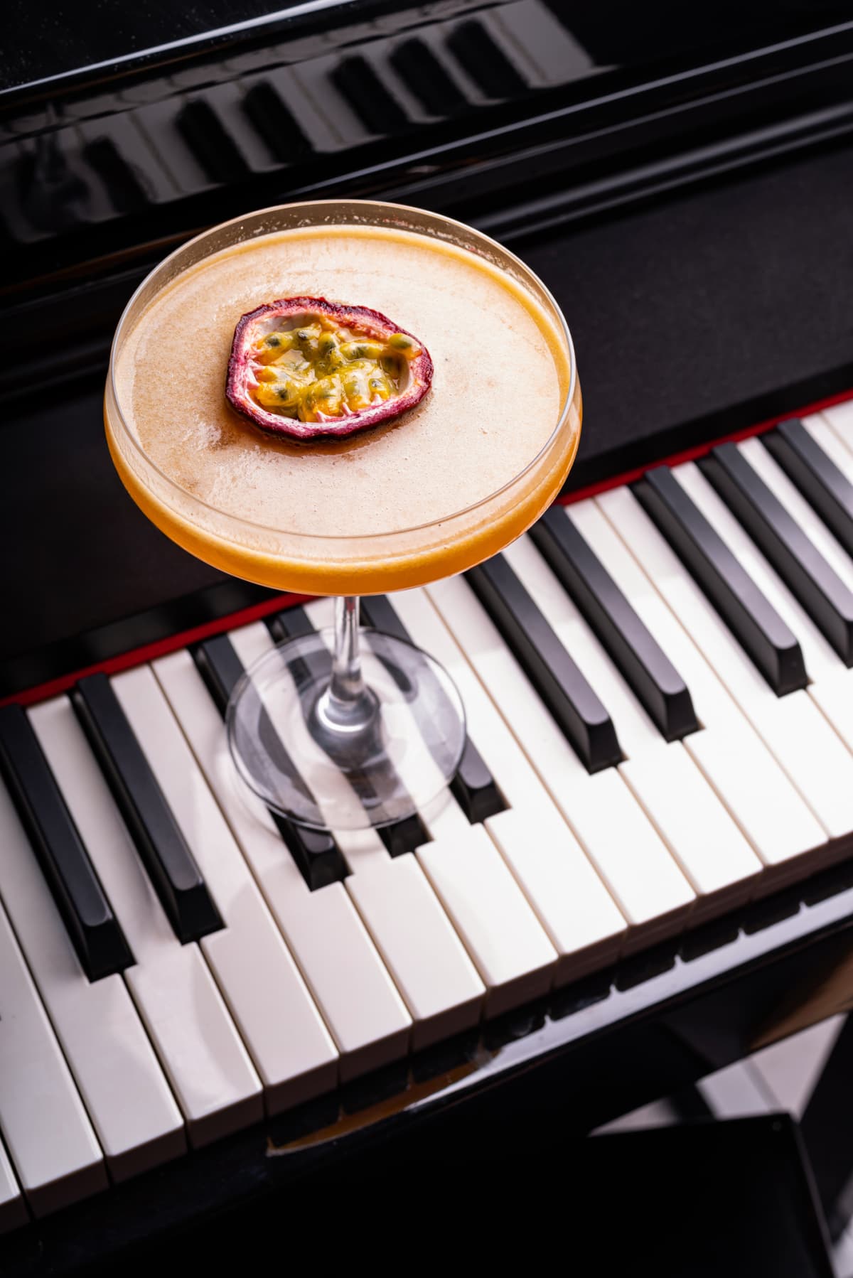 Pornstar Martini cocktail garnished with half of a passionfruit on a piano keyboard