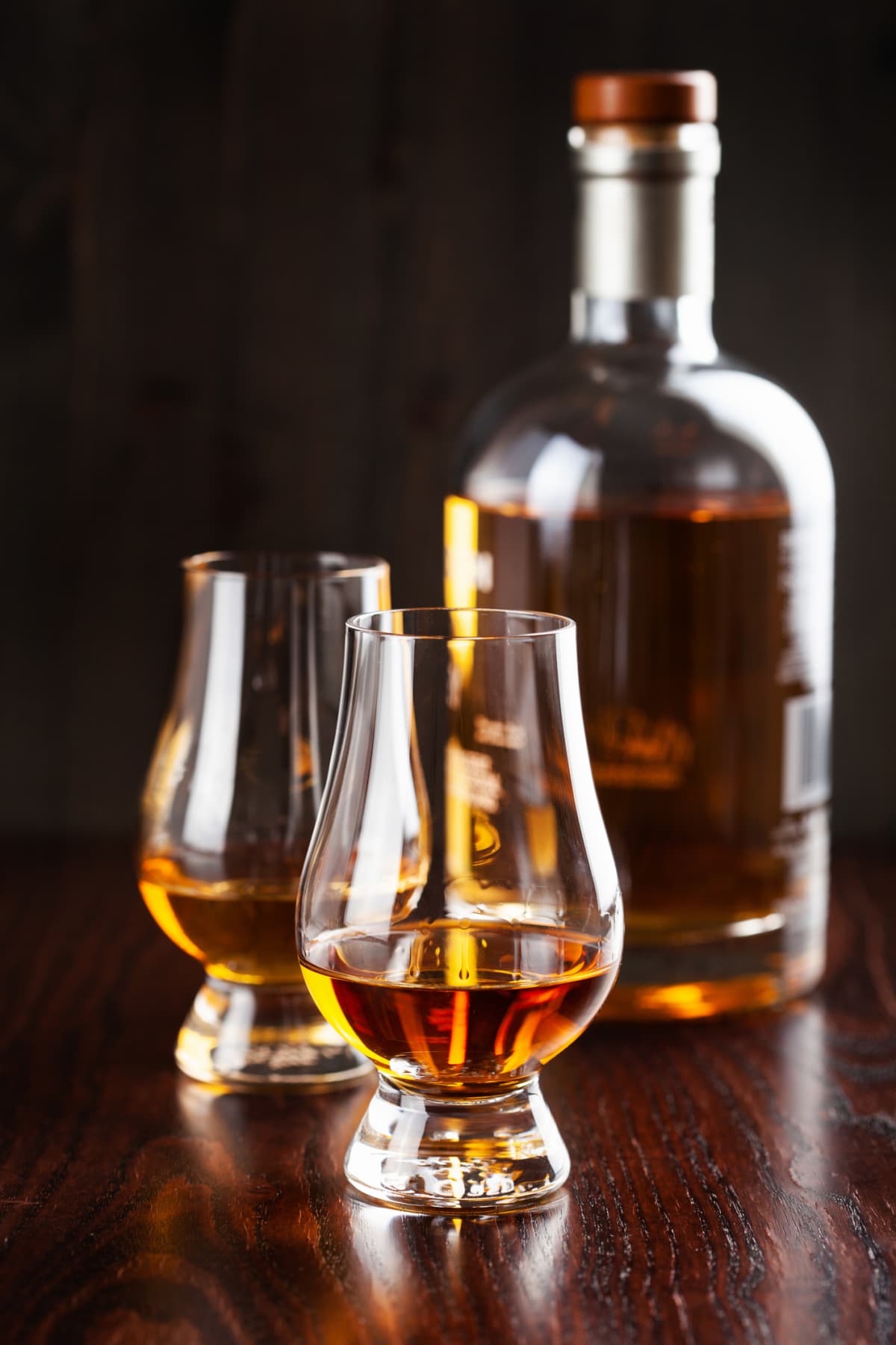 Bottles and glass of whisky spirit brandy on dark brown background