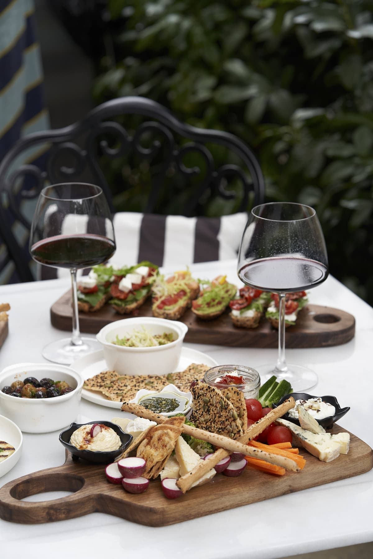 Italian antipasti wine snacks on table. Red wine glasses, cheese variety, bruschetta, olives, prosciutto, outdoor party