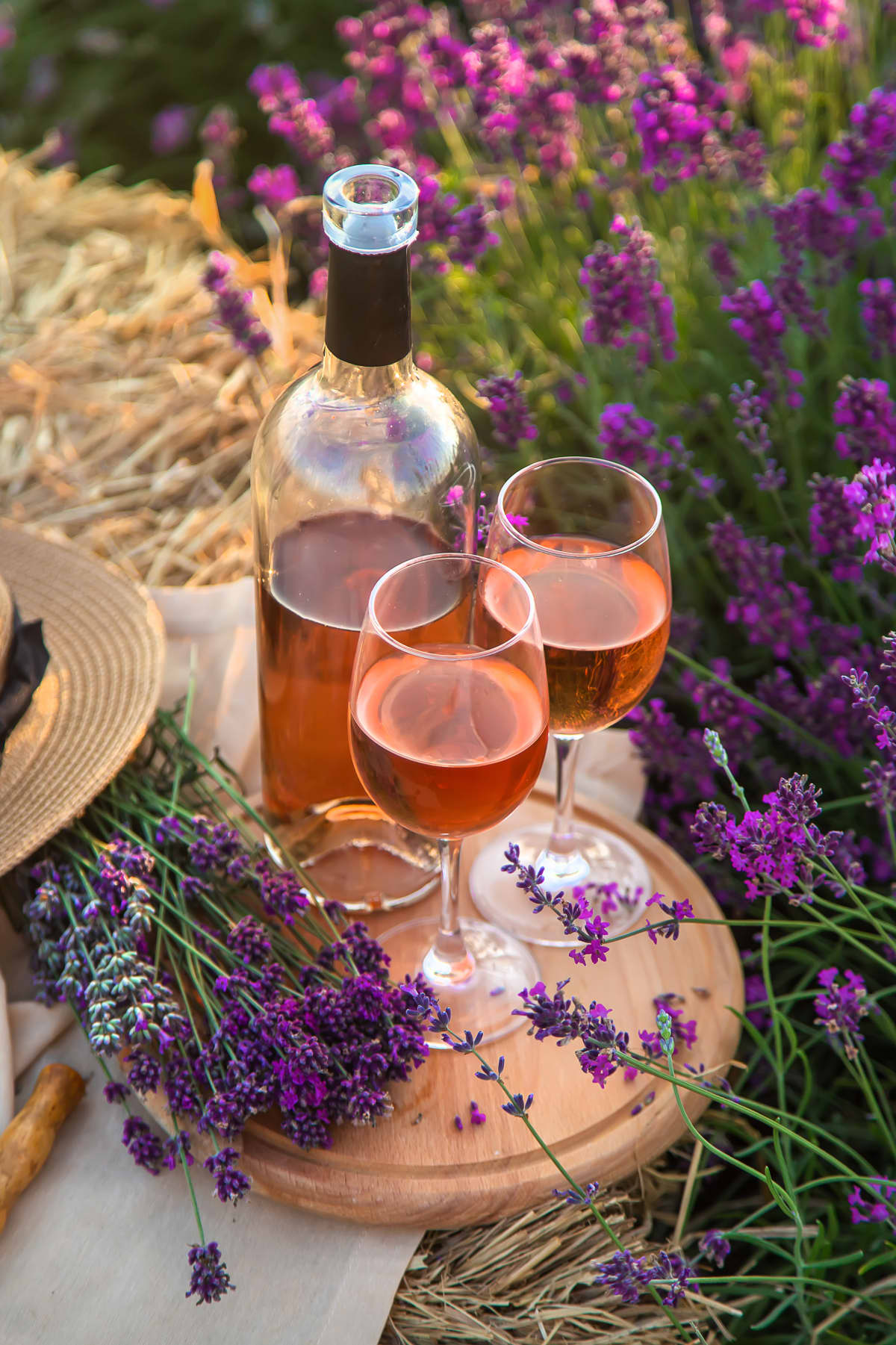 Pink wine bottle and two glasses in a field of lavenders