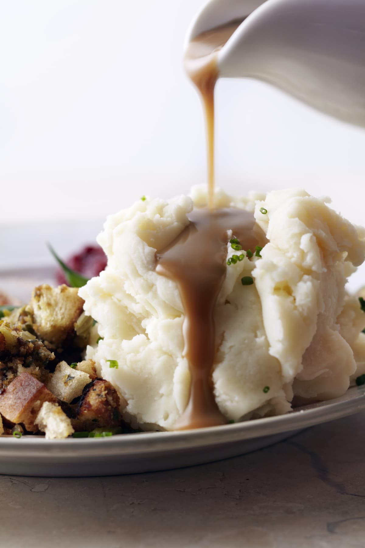 Gravy getting poured on mashed potatoes on a plate 