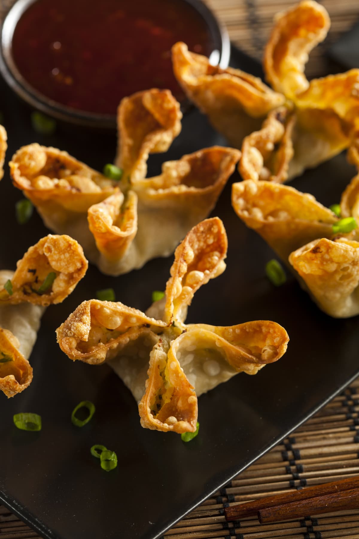 Crab rangoons with sliced onions and sweet and sour sauce