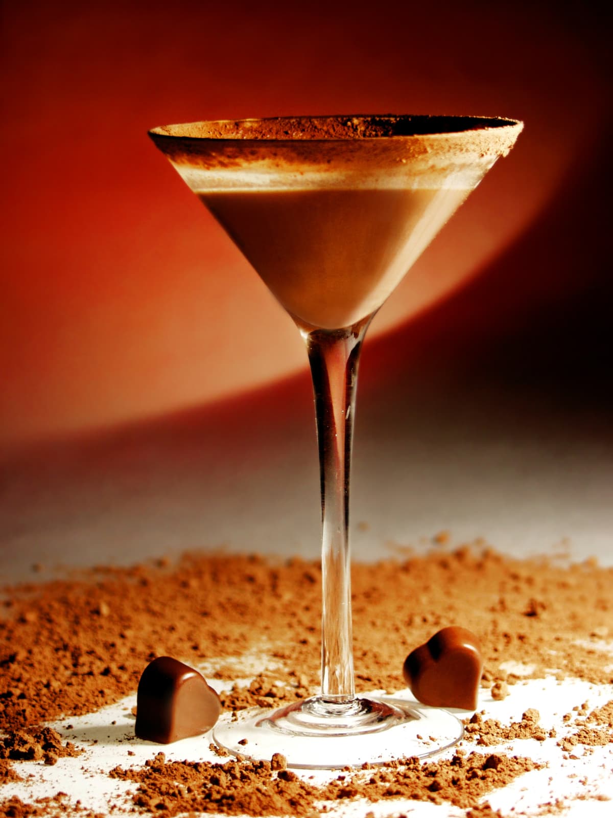 Chocolate martini surrounded by cocoa powder and chocolate candies.