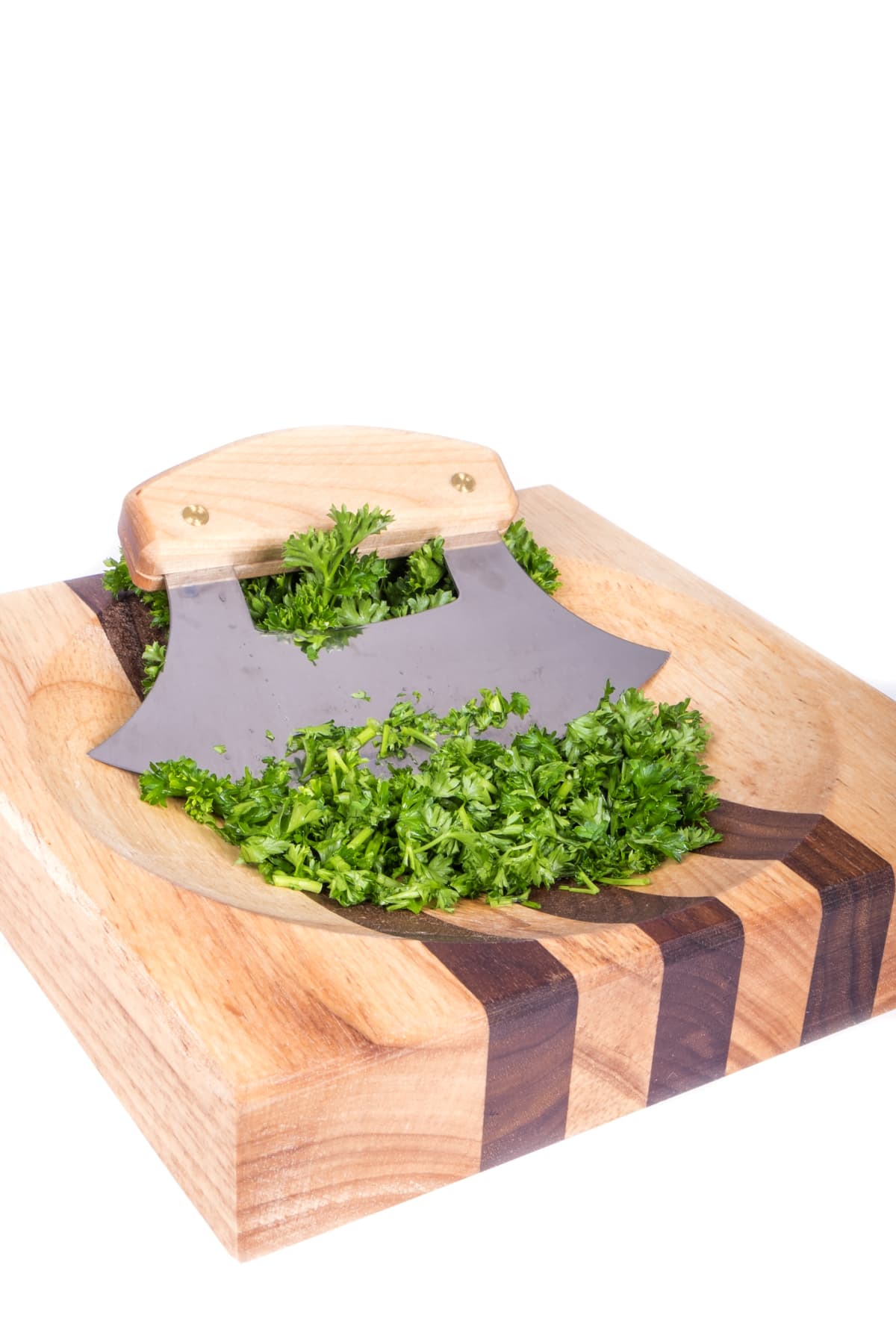 An Alaskan ulu knife and chopped green parsley on a striped wooden chopping block isolated on white.