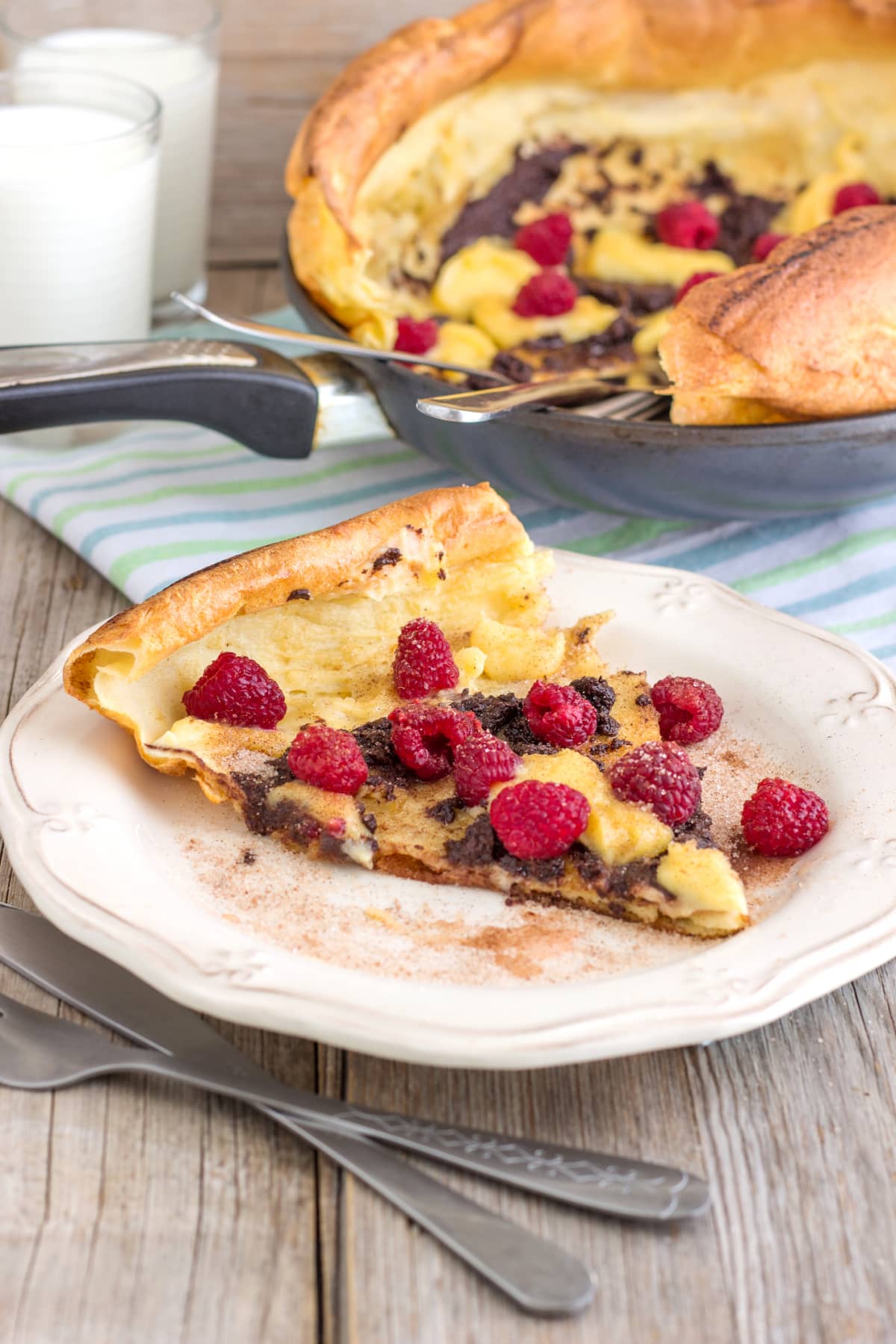 Slice of Dutch baby topped with raspberries on plate