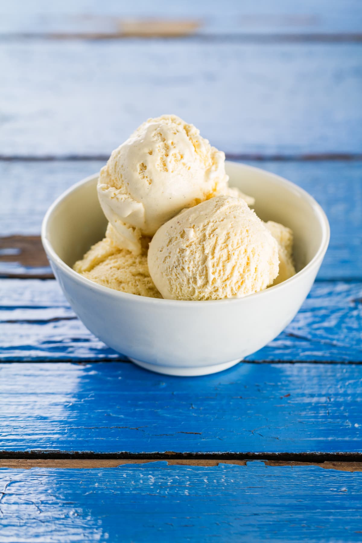 Tasty vanilla ice scoops in bowl on blue wooden rustic table. Closeup.