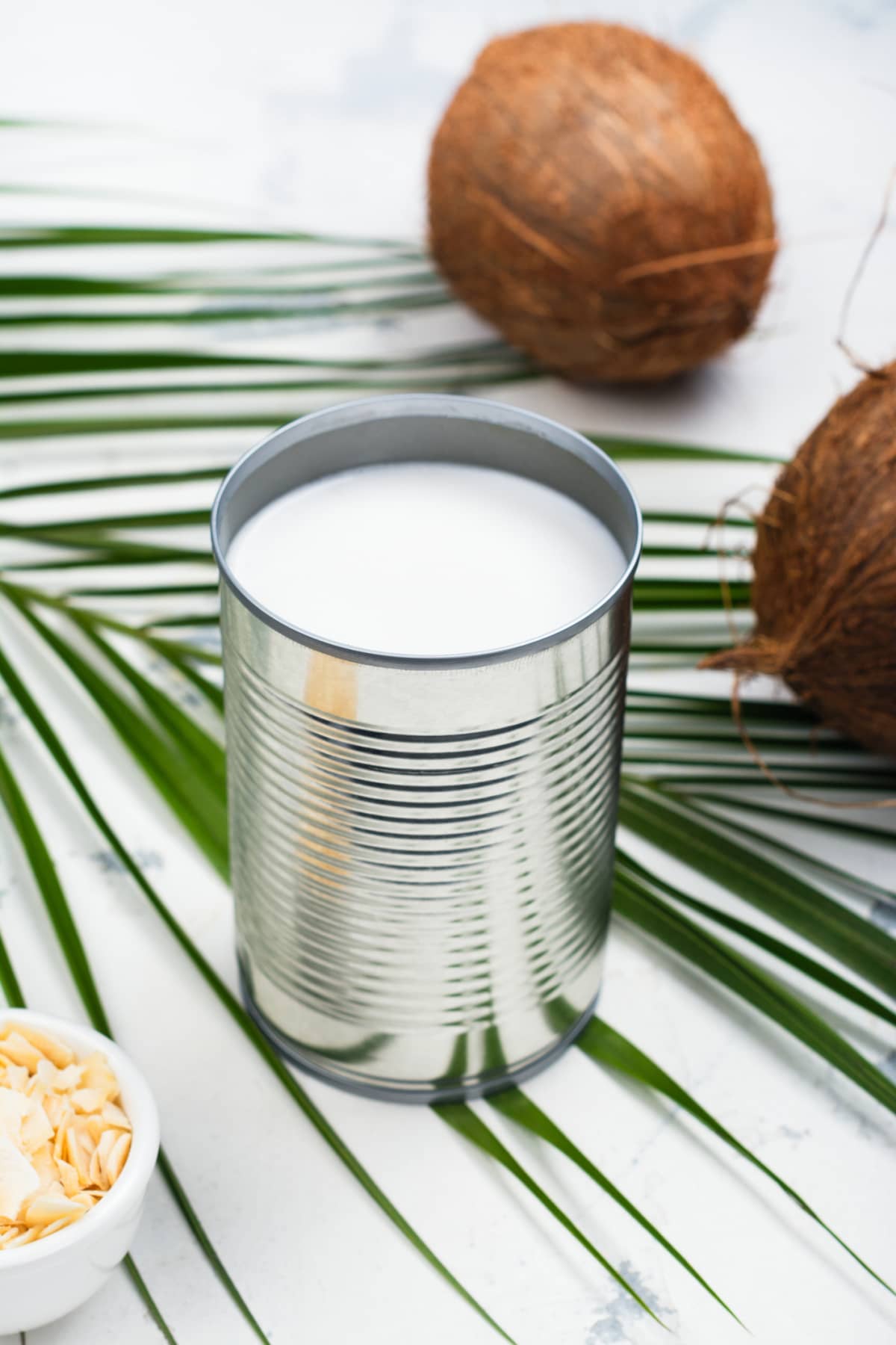 Opened tin can with coconut milk drink. Alternative non dairy vegan milk on white stone table