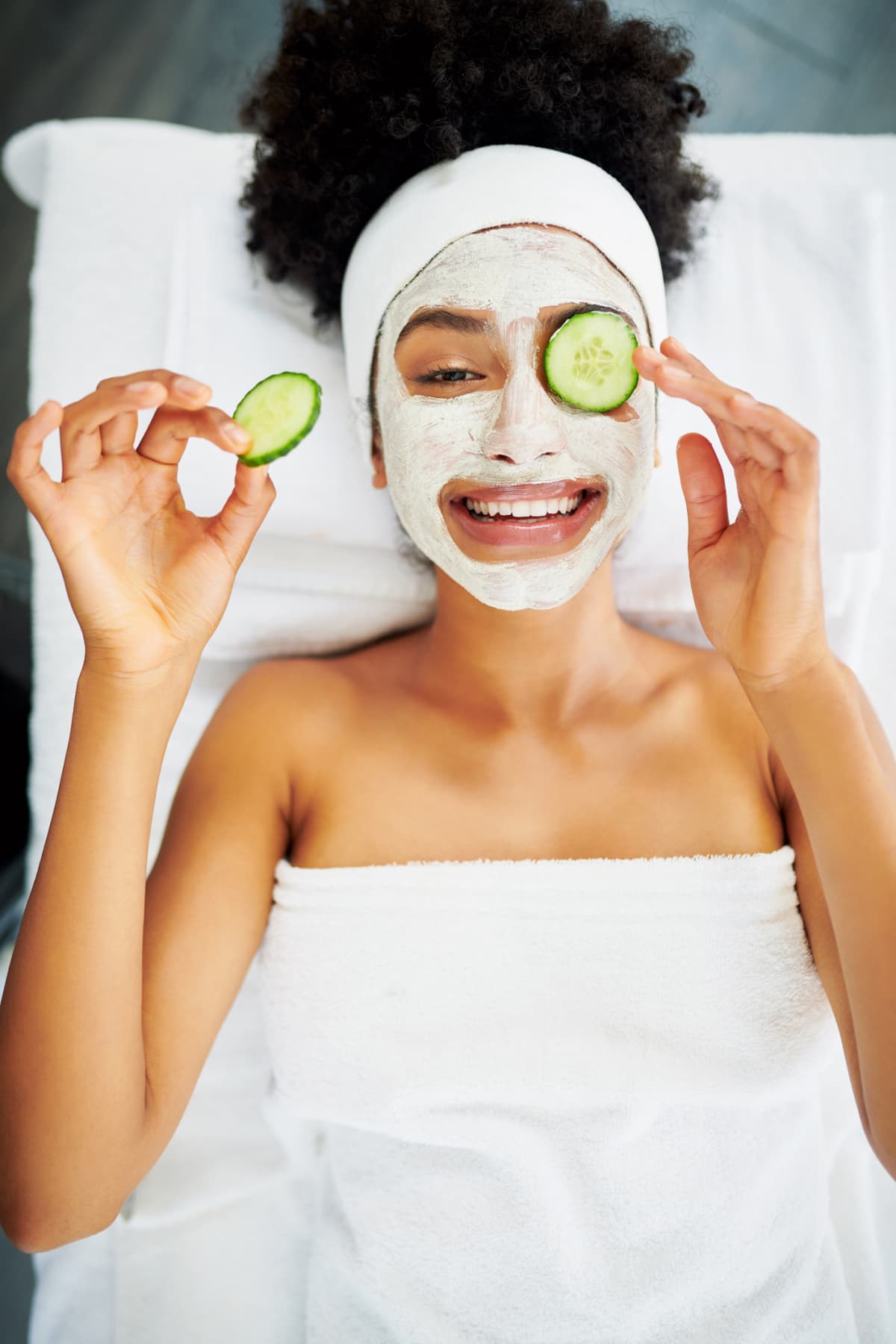 woman with face mask and cucumber slices on her eyes