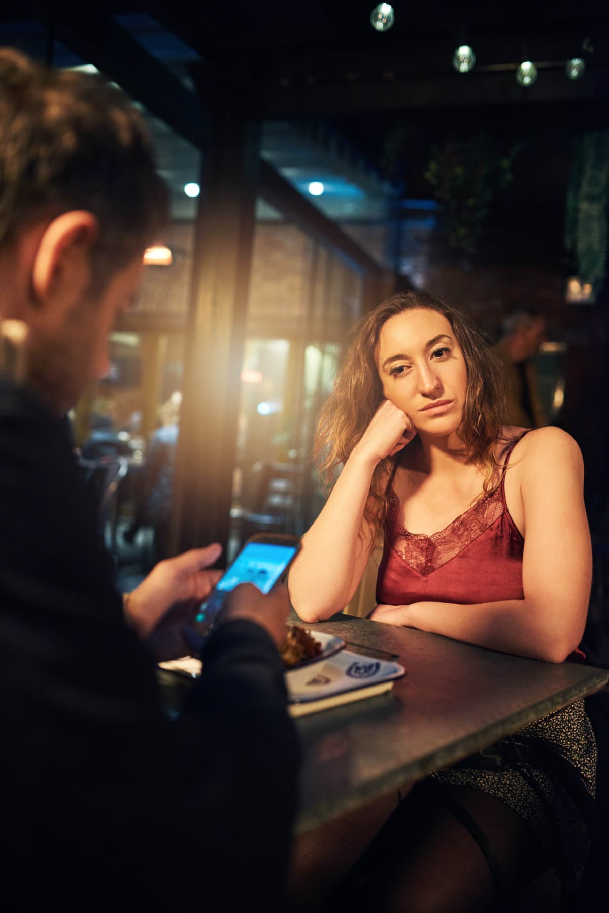 man on phone during date woman looks annoyed