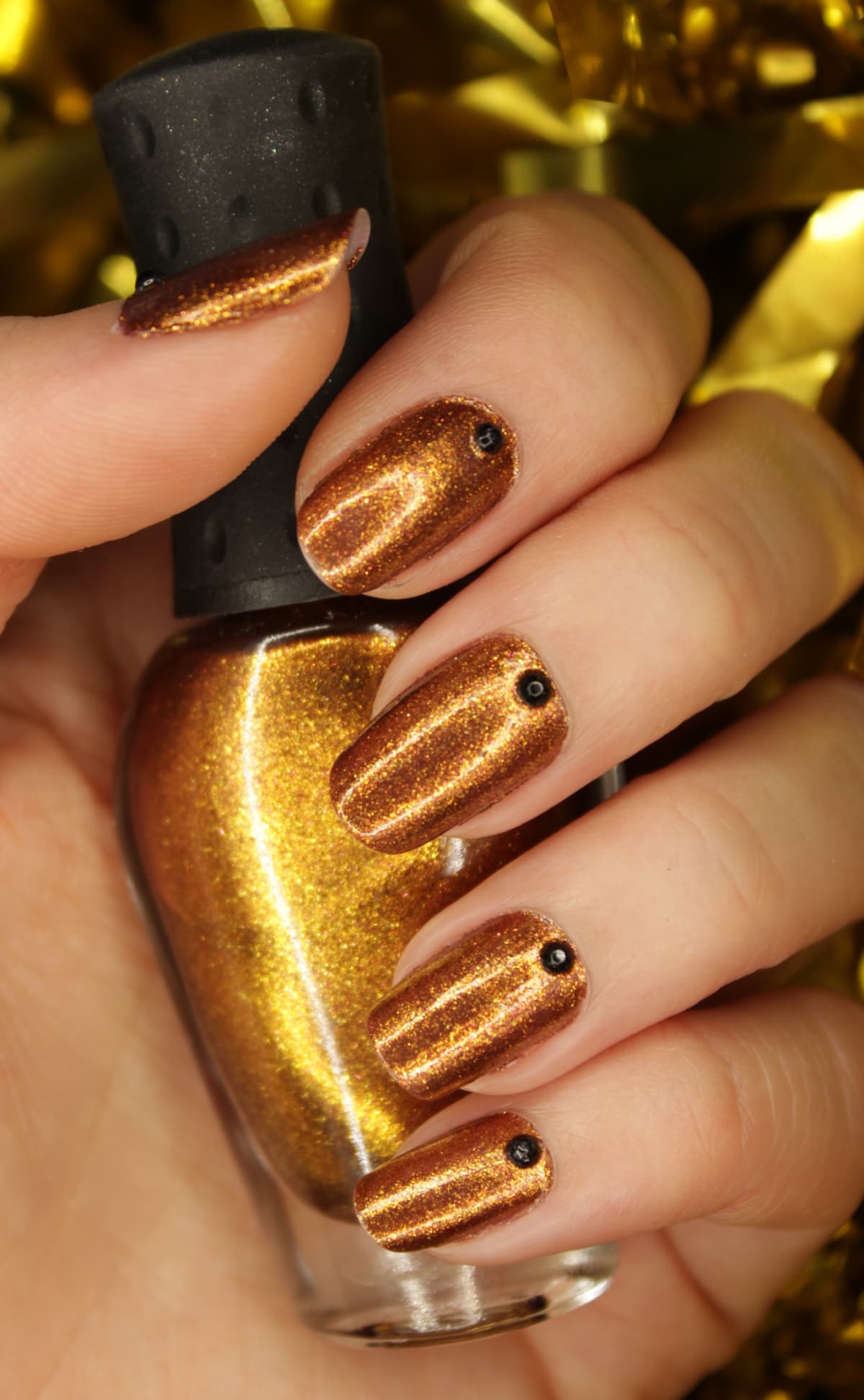 nails with gold nail polish holding nail polish bottle