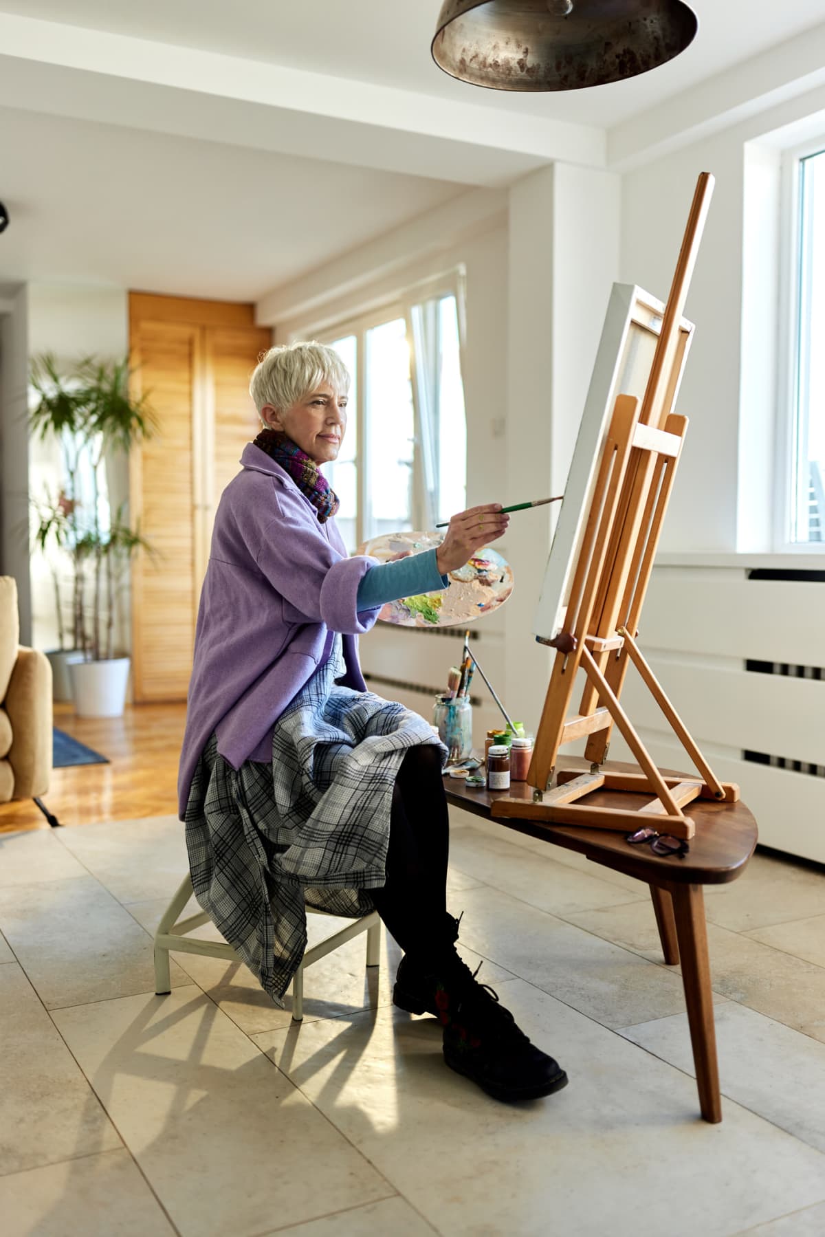 woman painting on an easel in her home