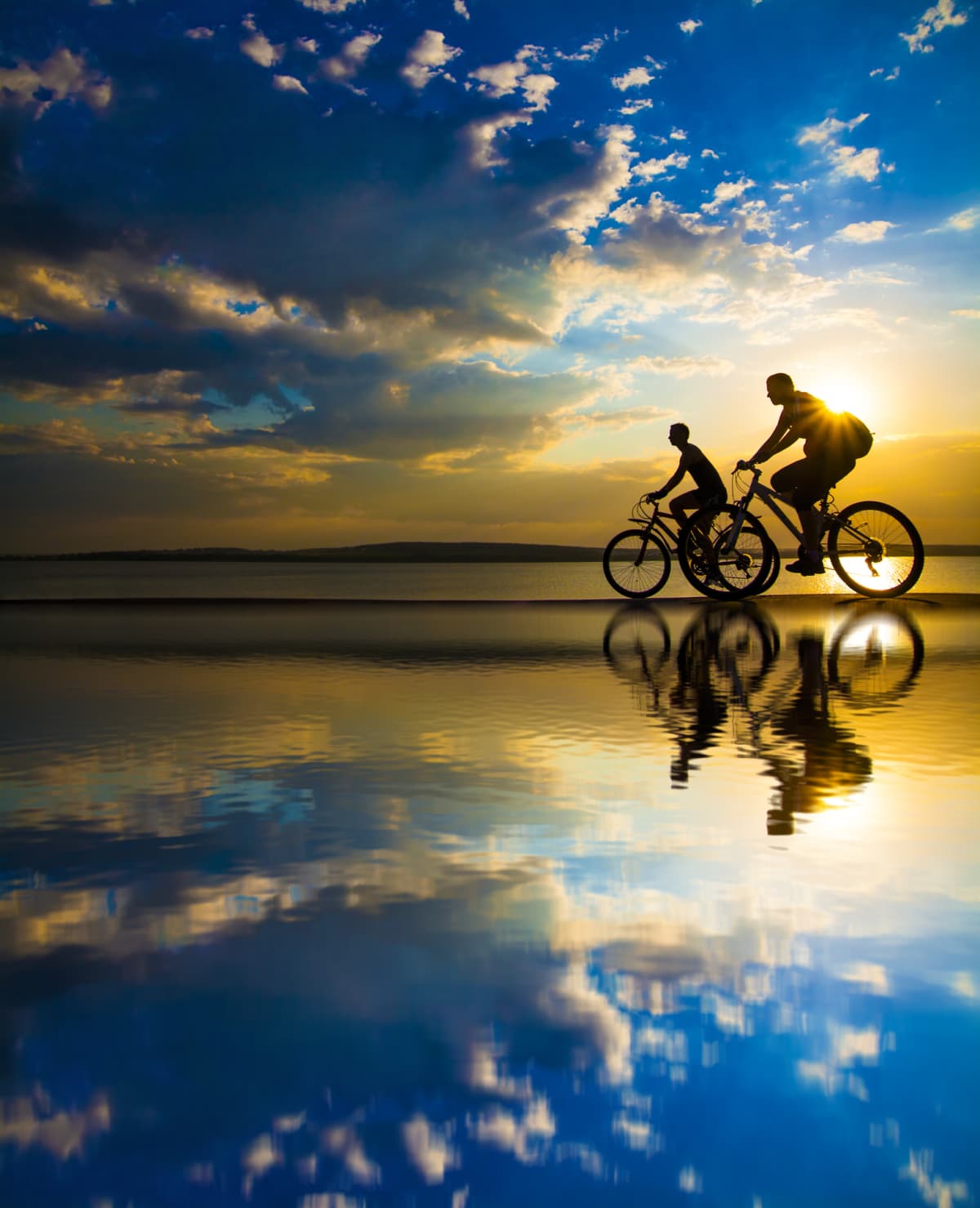 Two people riding bikes on the beach