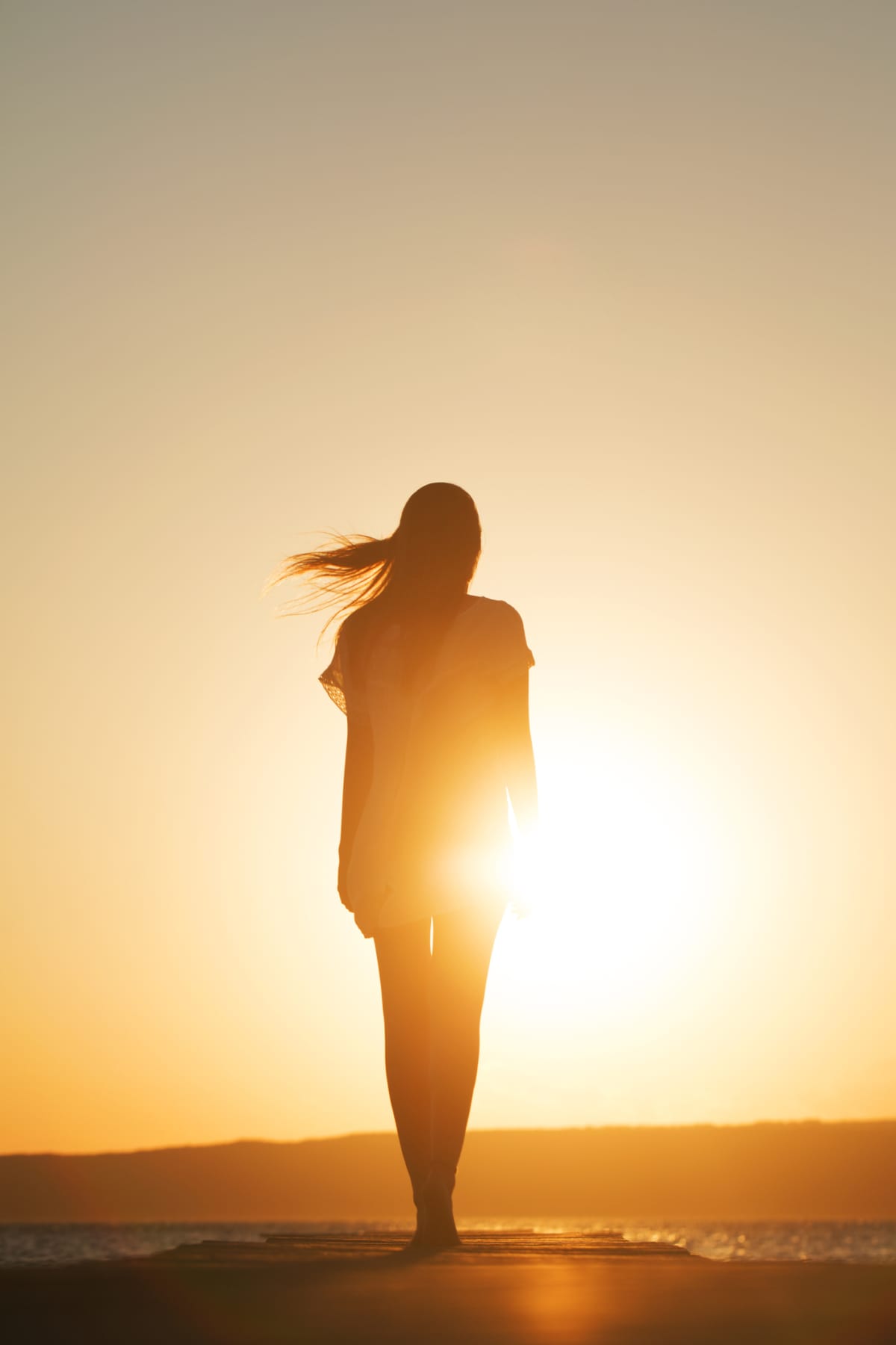 A silhouette of a woman facing the sun