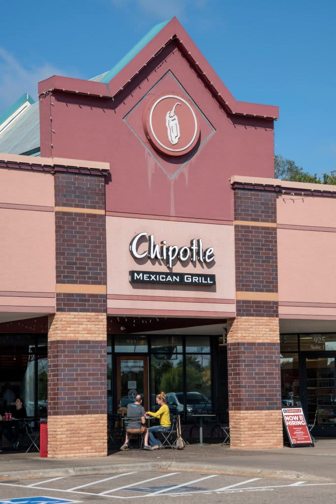 Vadnais Heights, Minnesota, Couple eating outside on patio at Chipotle Mexican Grill with a now hiring sign. It is an American chain of fast casual restaurants specializing in tacos and Mission burritos that are made to order for the customer. (Photo by: Michael Siluk/UCG/Universal Images Group via Getty Images)