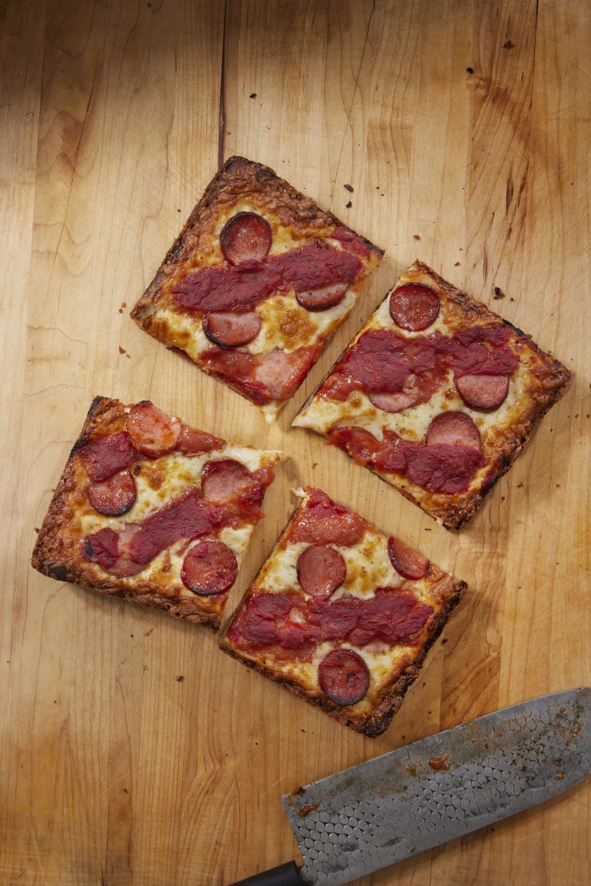 Square slices of a non-veg, thin-crust pizza.
