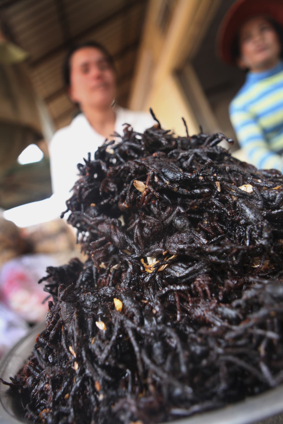 This photo taken on March 14, 2018 shows a live tarantula crawling across a man's shirt with a Cambodian flag at Skun town in Kampong Cham province.
While a plate piled high with hairy, palm-sized tarantulas is the stuff of nightmares for some, these garlic fried spiders are a coveted treat in Cambodia, where the only fear is that they may soon vanish due to deforestation and unchecked hunting. / AFP PHOTO / TANG CHHIN Sothy / TO GO WITH AFP STORY: CAMBODIA-LIFESTYLE-TARANTULAS-TOURISM-ENVIRONMENT-FOOD; Feature by SUY SE        (Photo credit should read TANG CHHIN SOTHY/AFP via Getty Images)