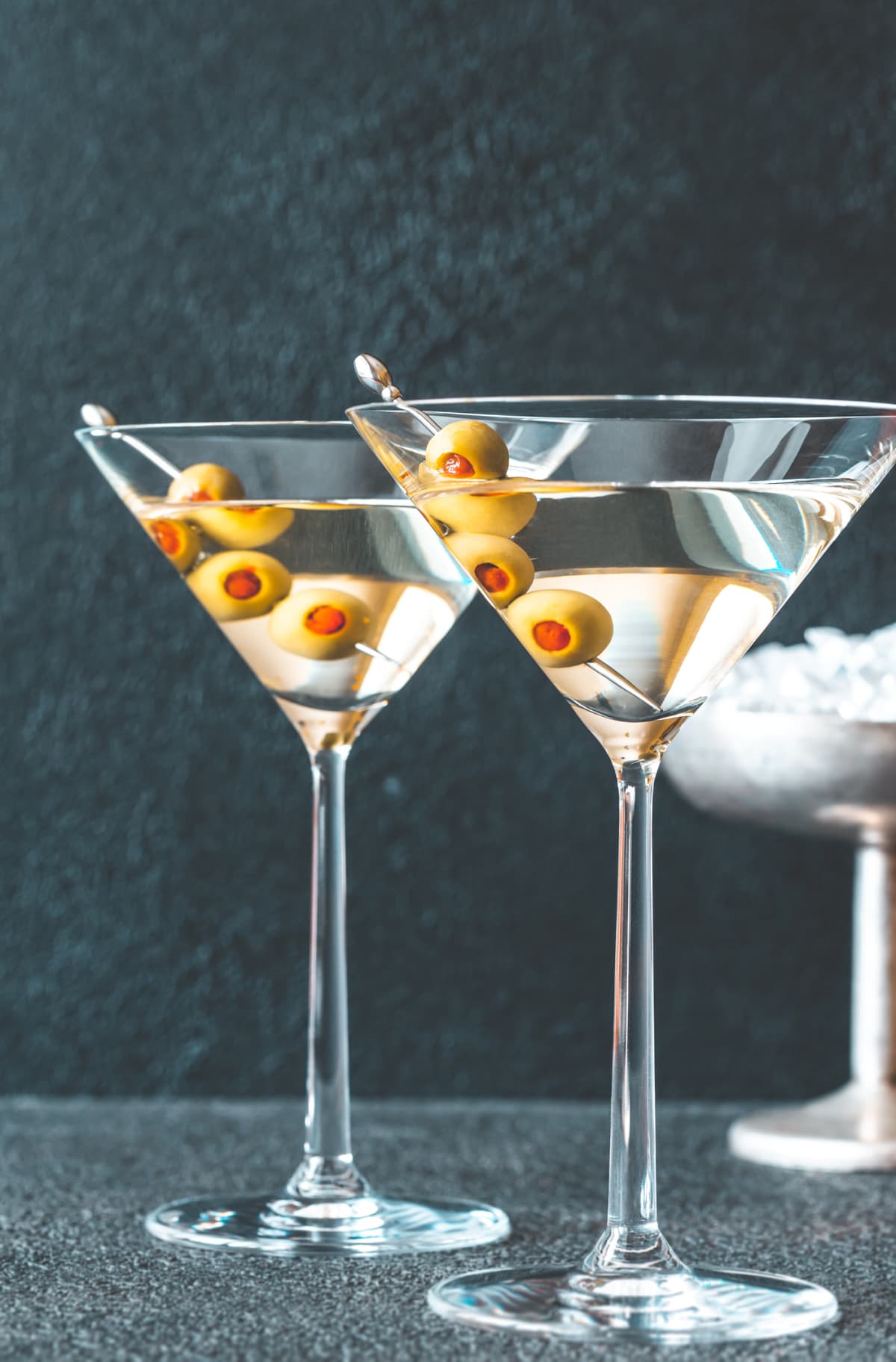 Two glasses of martini cocktail garnished with green olives